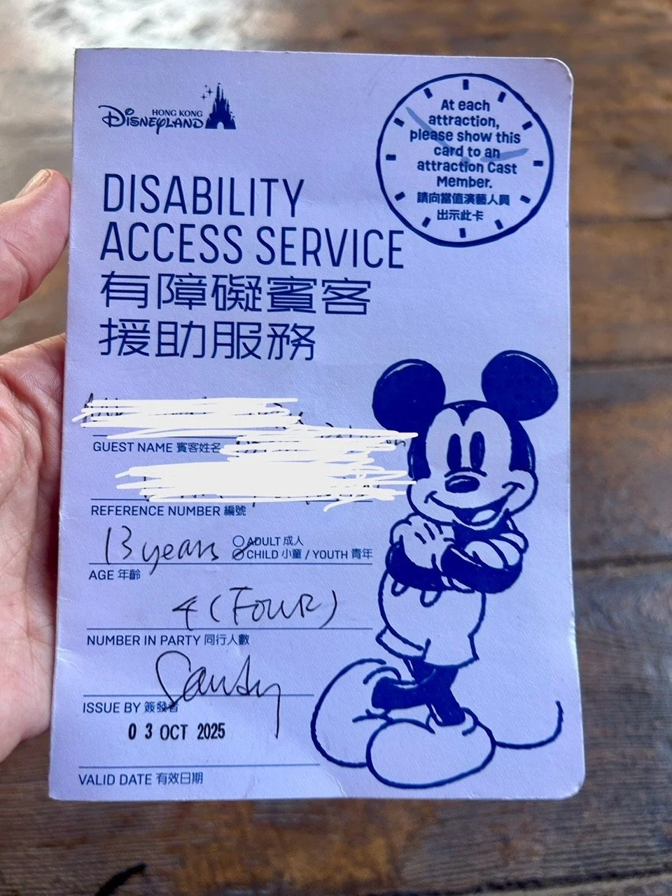 Disability Access Service card from Hong Kong Disneyland featuring Mickey Mouse illustration, with details including guest name, reference number, age, party size, issue date, and valid date.