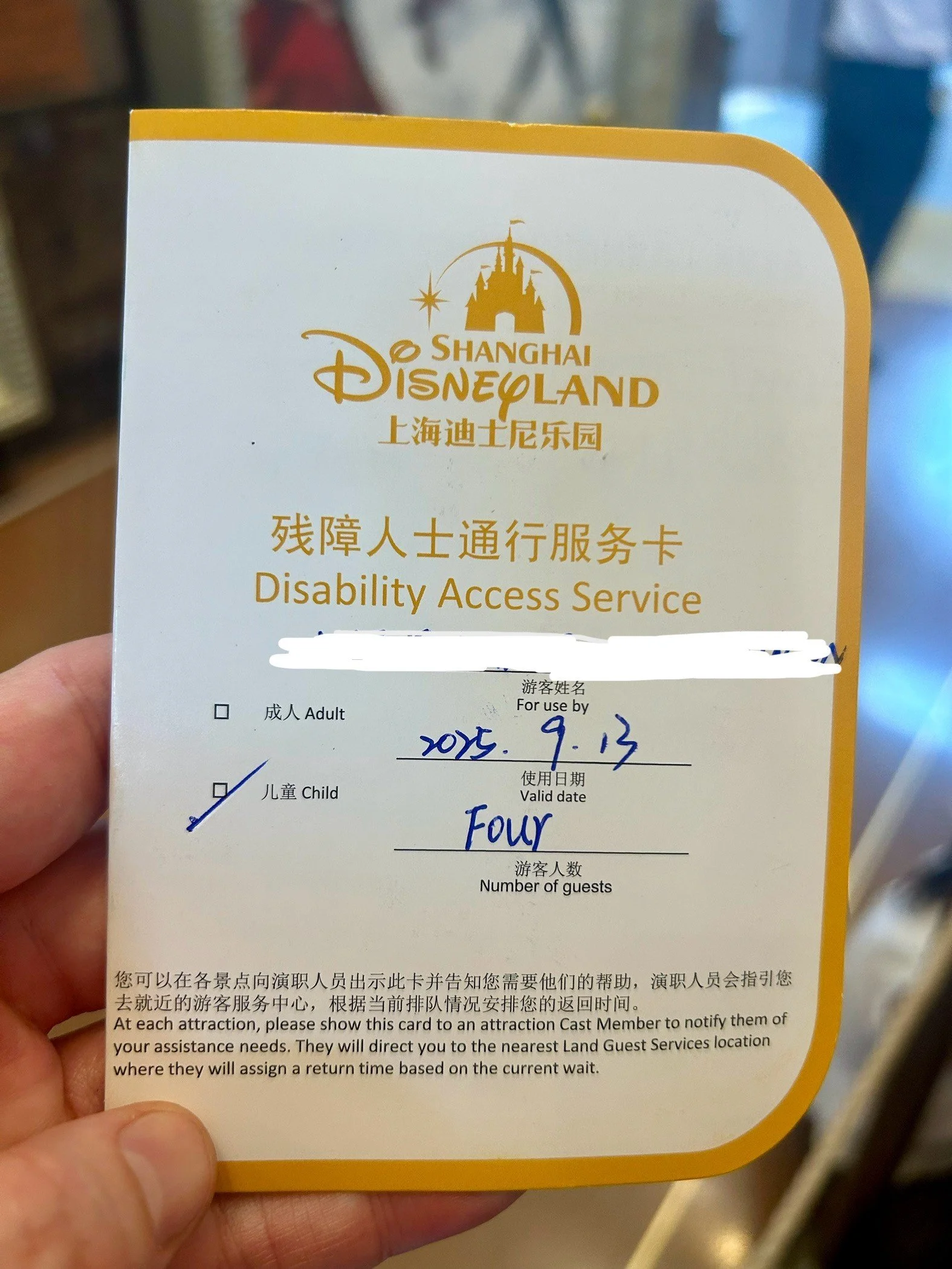 A Shanghai Disneyland Disability Access Service card displaying a valid date of September 13, 2015, for four guests, with some text in Chinese and English.