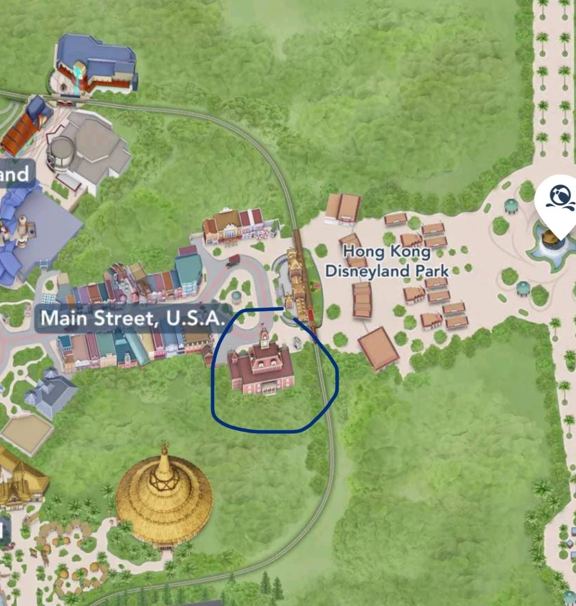 Map of Hong Kong Disneyland Park showing Main Street, U.S.A., a train station, and surrounding areas, with a blue circle highlighting a building.