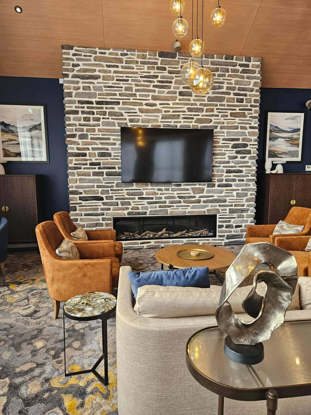 Warm, textural living space with natural stone fireplace and layered, wellness-focused interior styling.