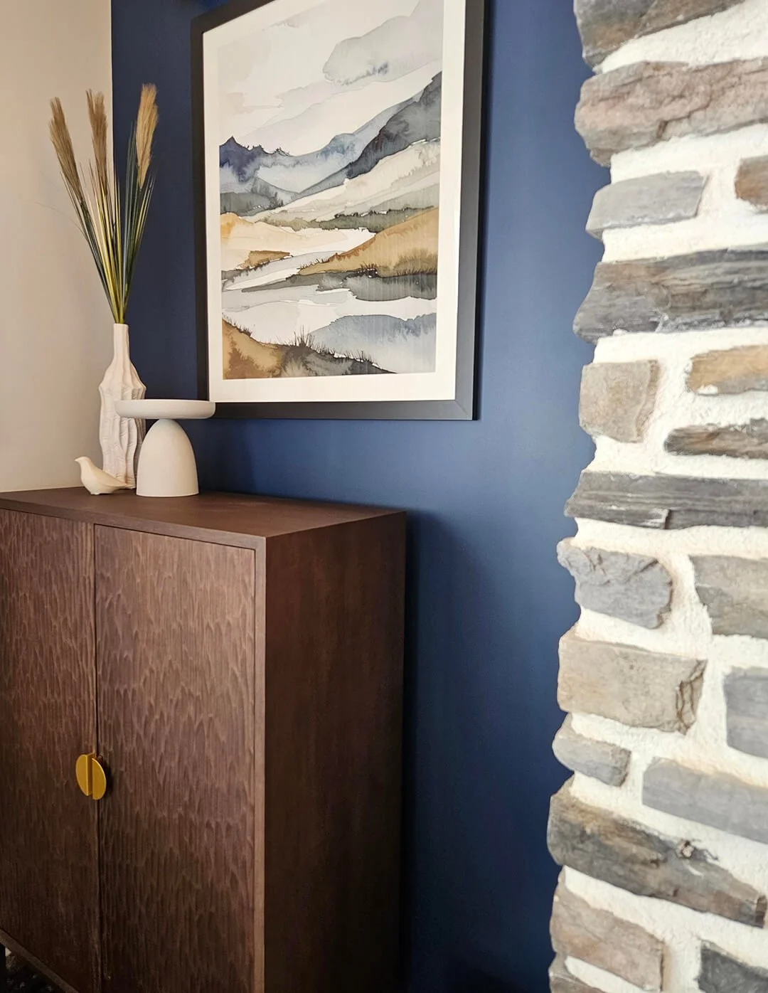 Styled interior corner with timber cabinetry and stone wall, balancing texture and warmth.