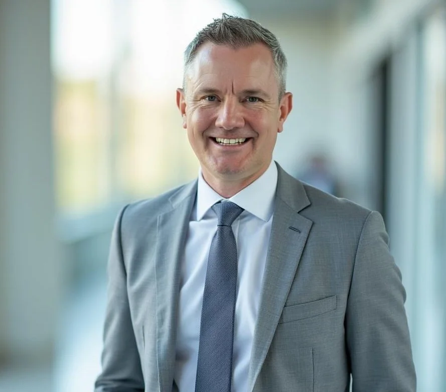 Man in gray suit and tie smiling in a professional setting