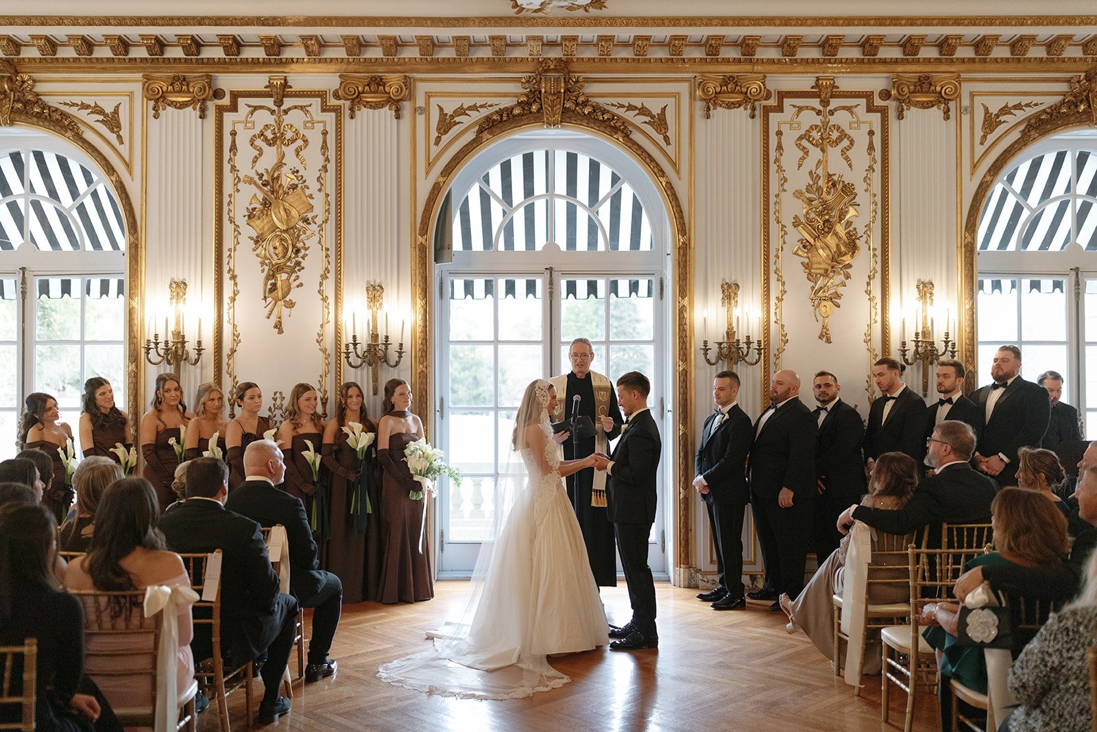 Photo of indoor wedding ceremony at Elstowe Manor in Elkins Estate. Bride and Groom sharing vows featuring classic architecture and timeless styling.