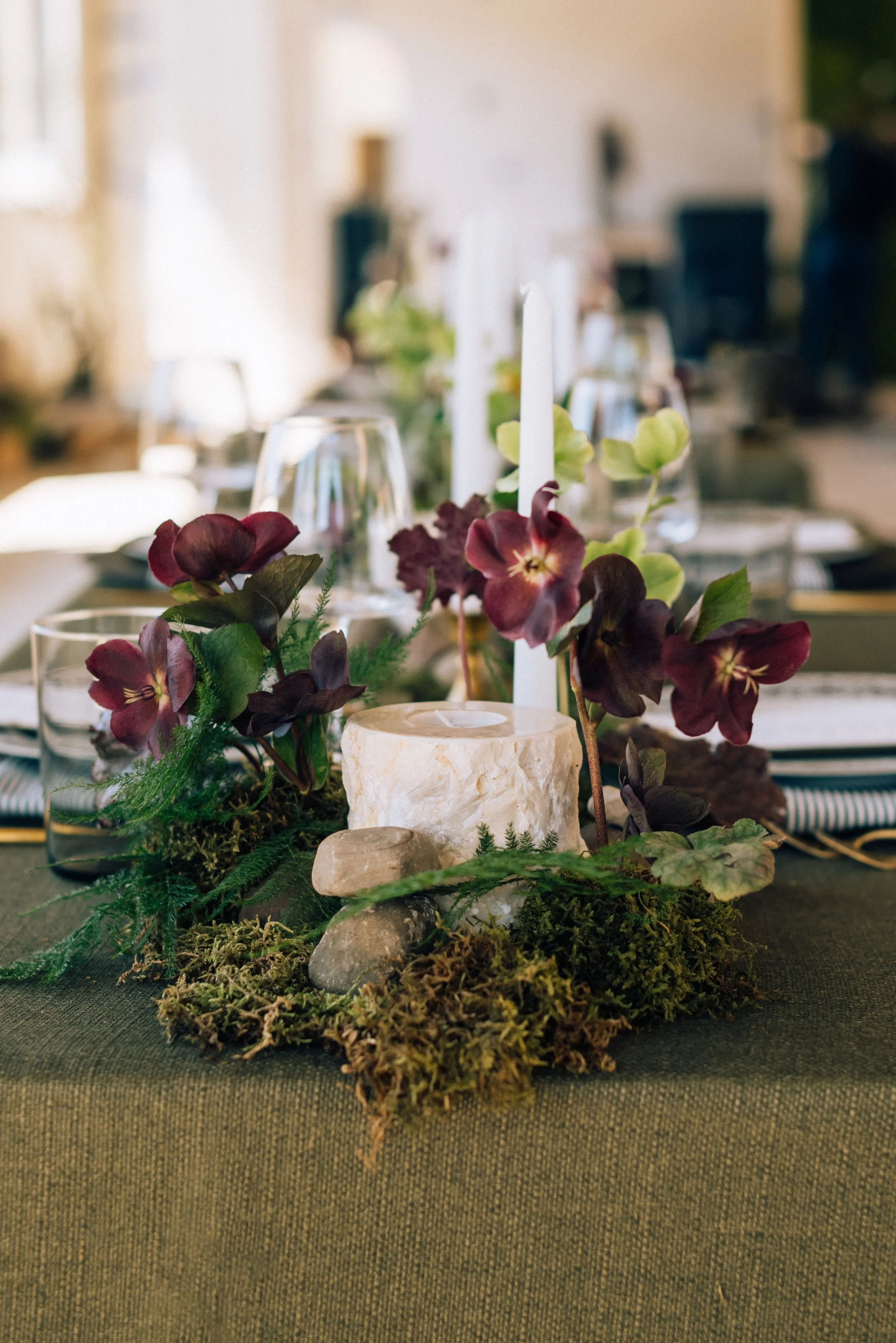 Purple-toned floral arrangement with forest-inspired greenery at wedding reception at The Arbor Loft