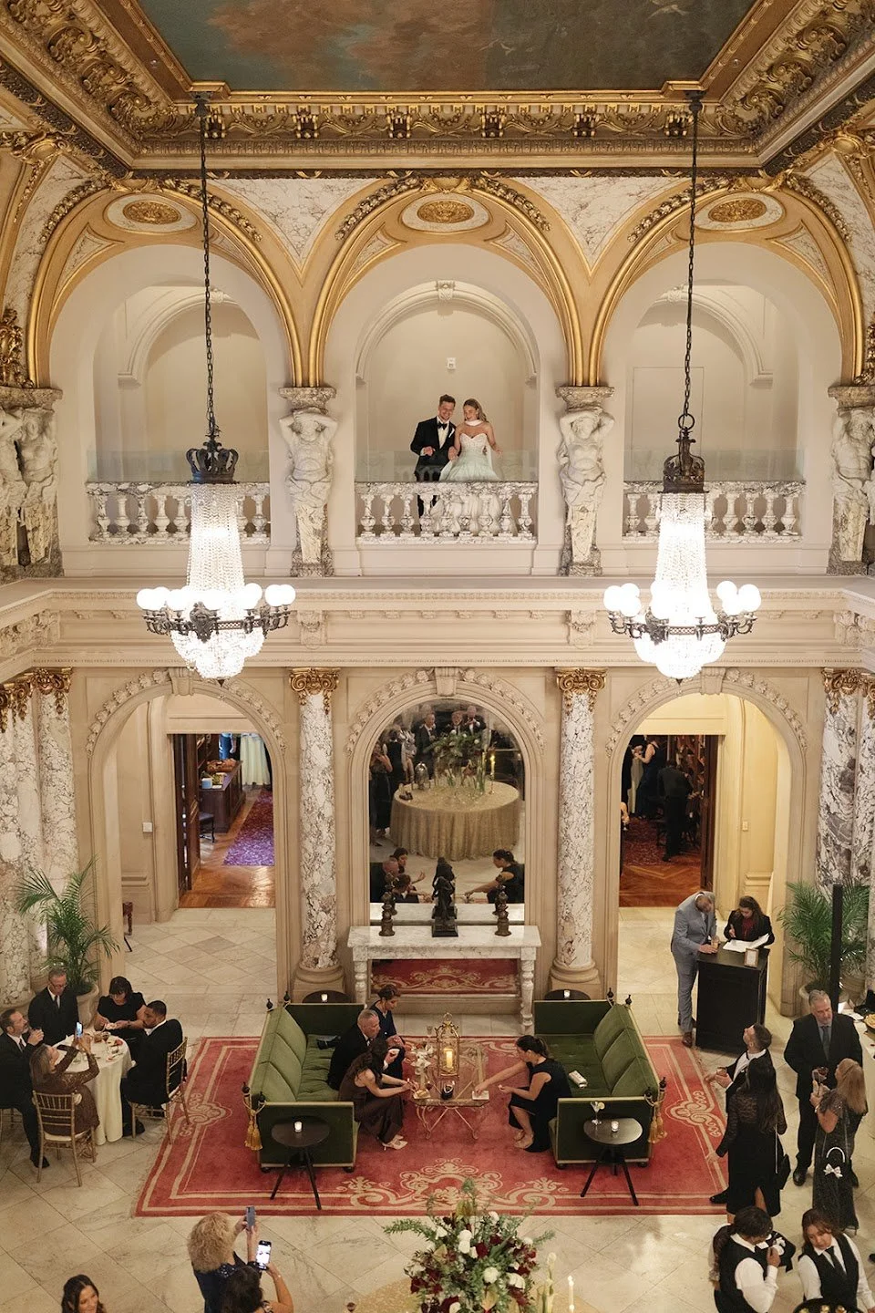 Bride and groom standing on balcony overlooking wedding guests at historical and architectural wedding venue in Elkins Park, Pennsylvania. Planned by Ember Event Management.