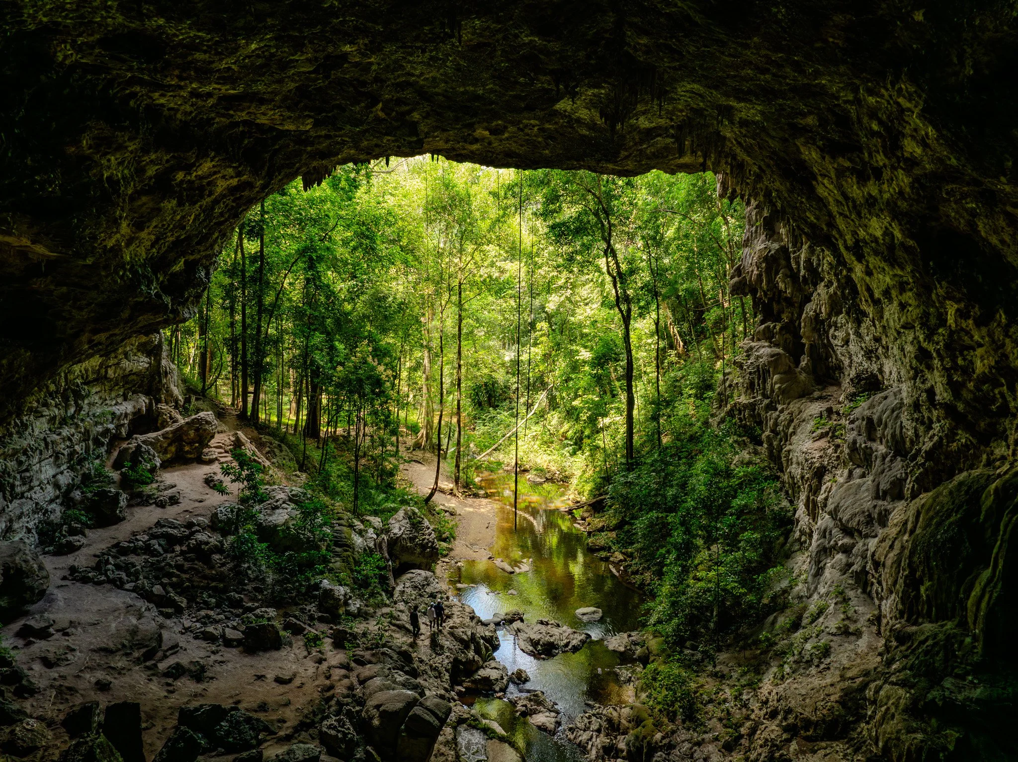 Guided through the river cave, two women on tubes are awestruck as their lamps illuminate a giant stalactite chandelier above them.