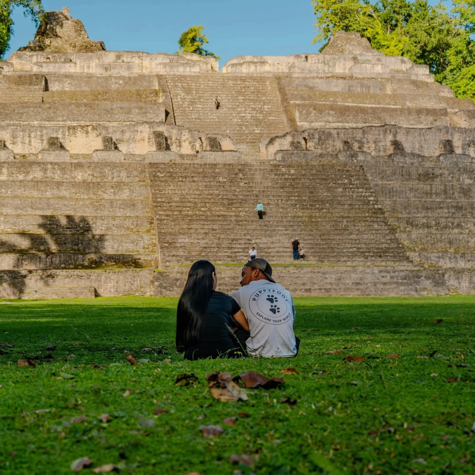 Fog drifts through the valleys of Caves Branch at dawn, painted in soft purple and orange light, contrasting with the vibrant green jungle hills.