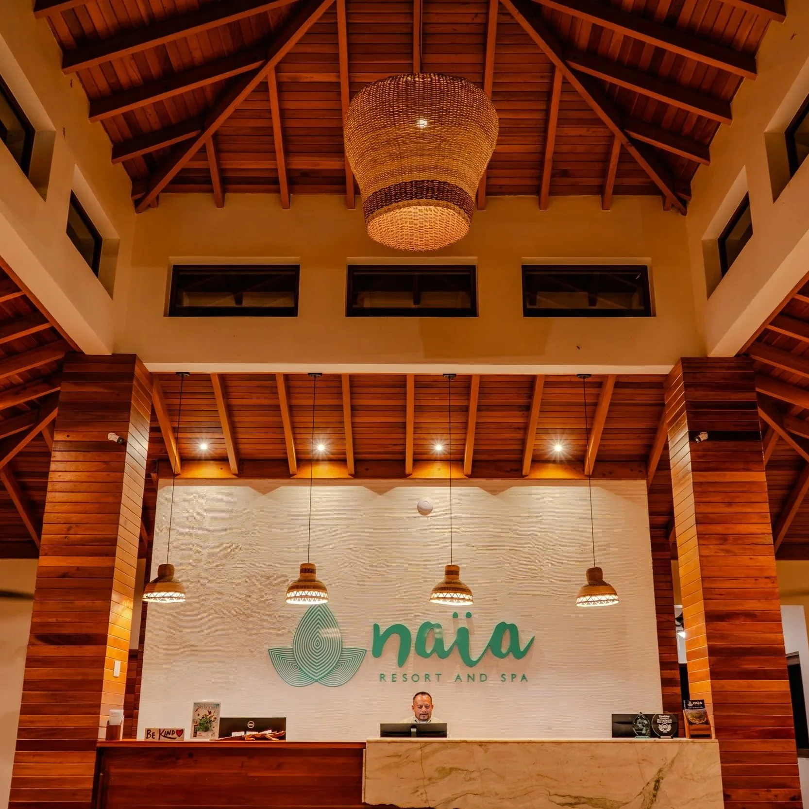 A perfectly symmetrical view of the grand, cathedral-style entrance at Naia Resort and Spa, featuring professional staff behind the reception counter.