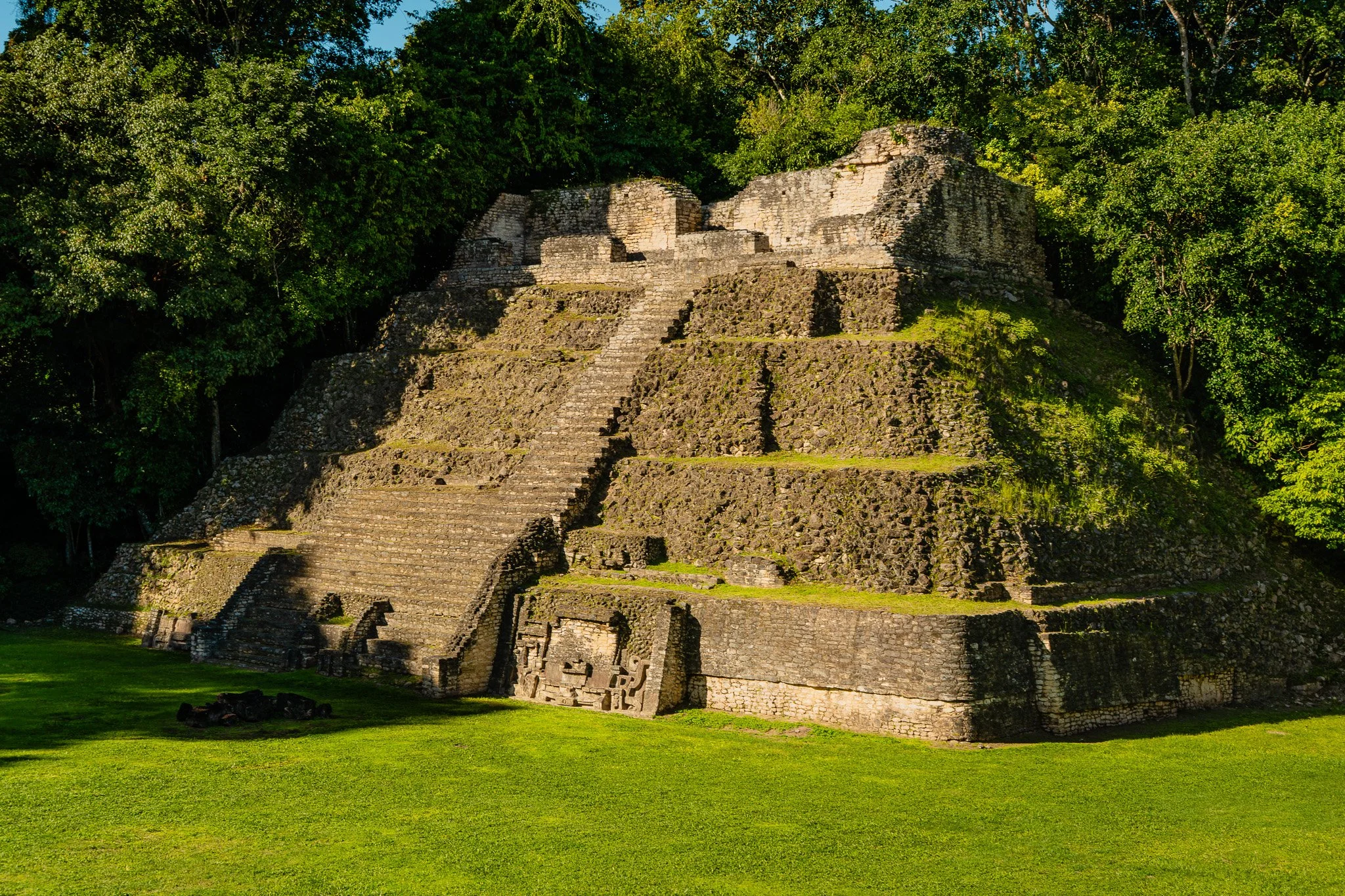 Under beautiful lighting, three women savor a buffet lunch atop an inverted kayak, set against the river’s edge with sweeping mountains and the river stretching behind them.