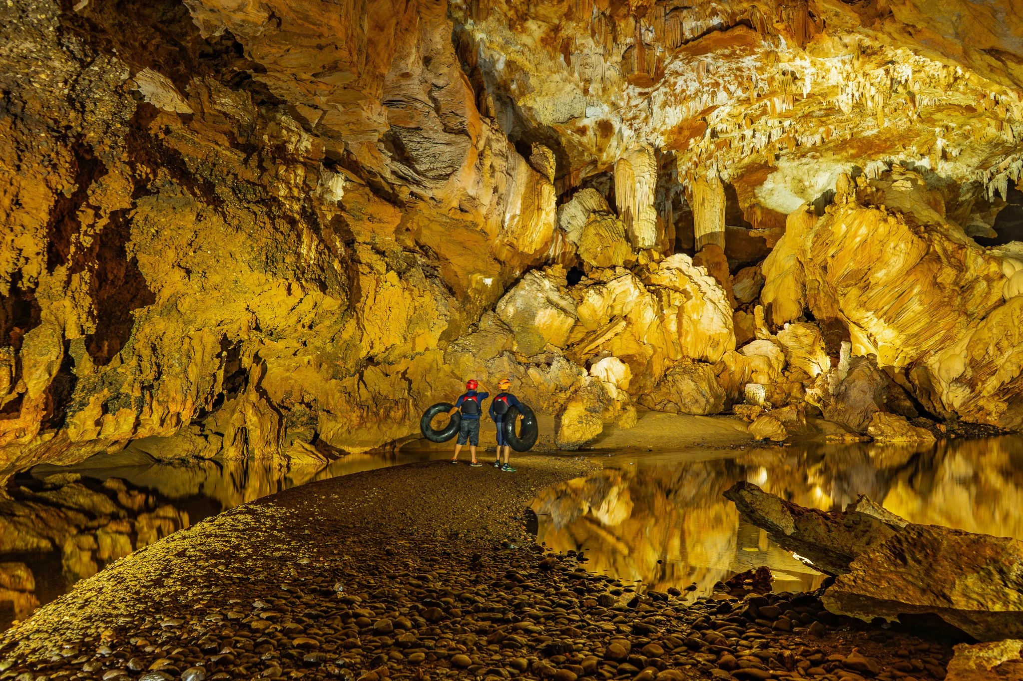 Beams of sunlight pierce the darkness of Caves Branch’s ceremonial cave, cascading through the sinkhole opening and lighting the interior in a dramatic glow.