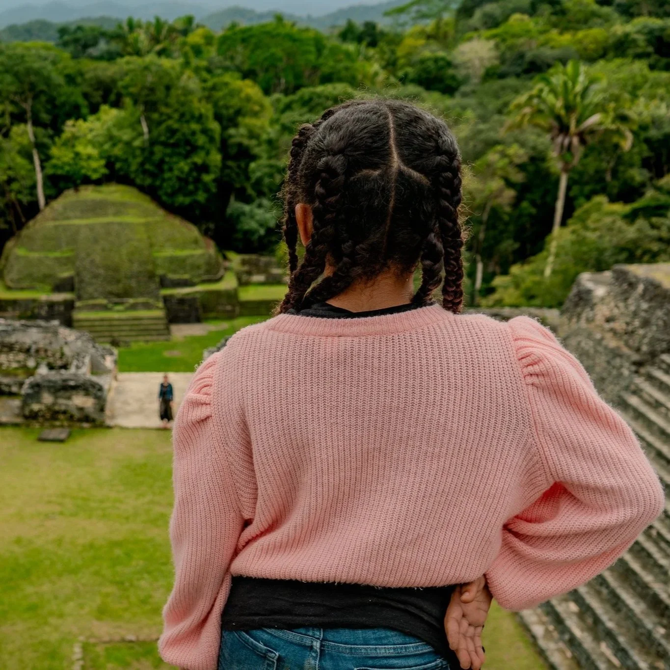 Suspended above the lush canopy, two women descend the Black Hole Drop Sinkhole, helmets and harnesses catching the light.