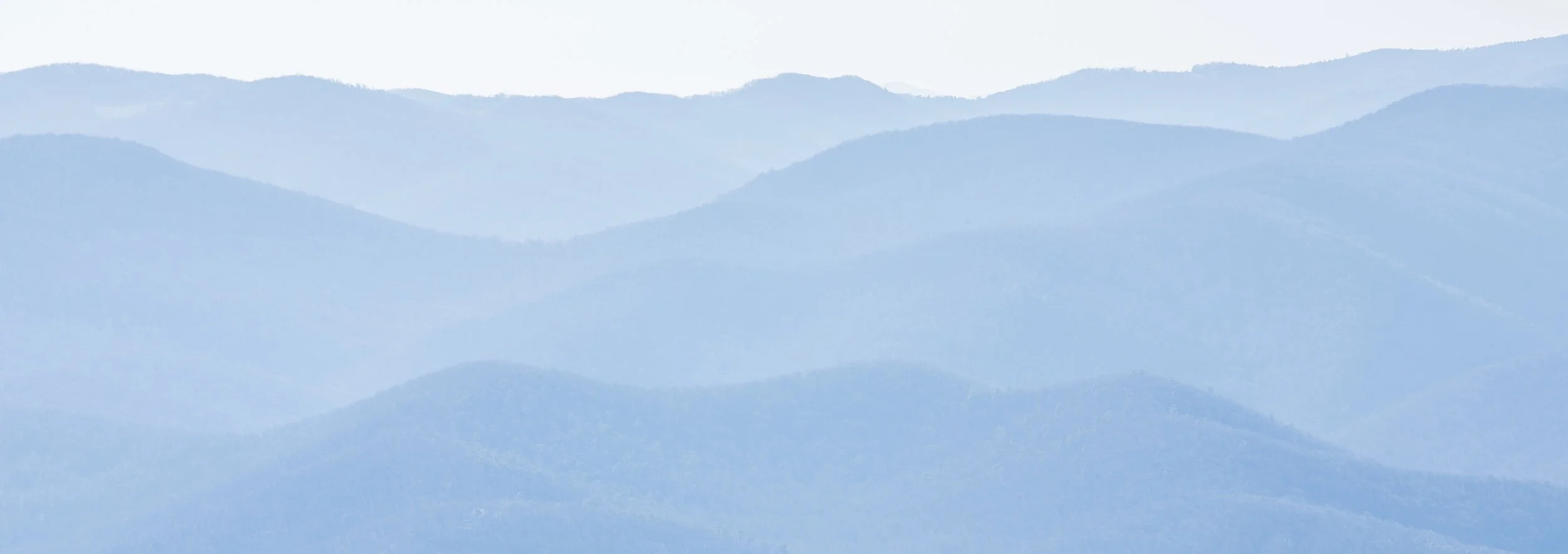 Mountain range with layered silhouettes and a foggy atmosphere.