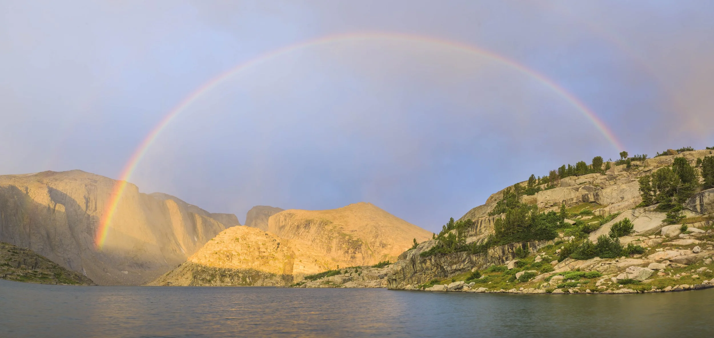 Scenic mountain landscape with a lake and a rainbow