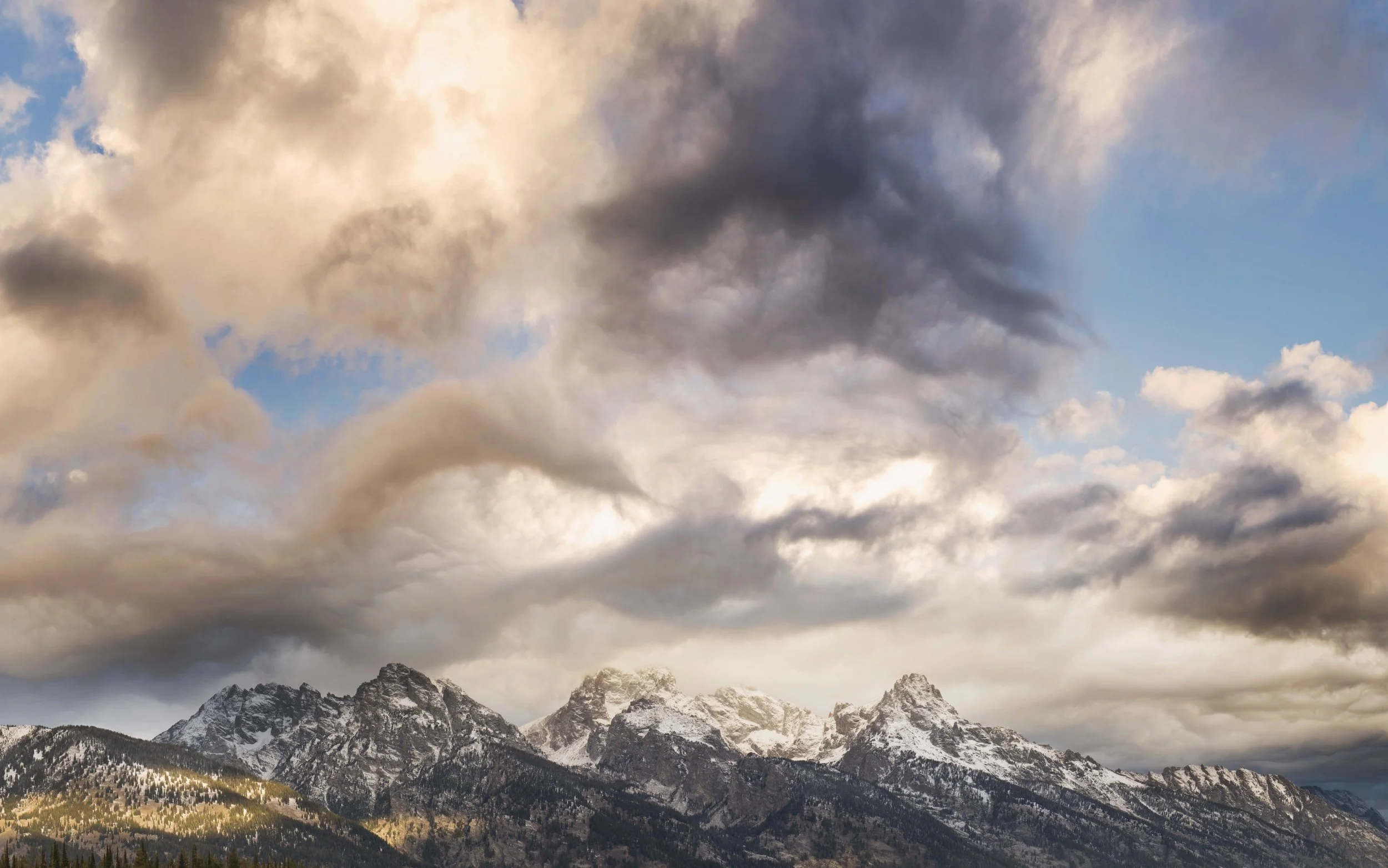 Snow-capped mountains under cloudy sky at sunset