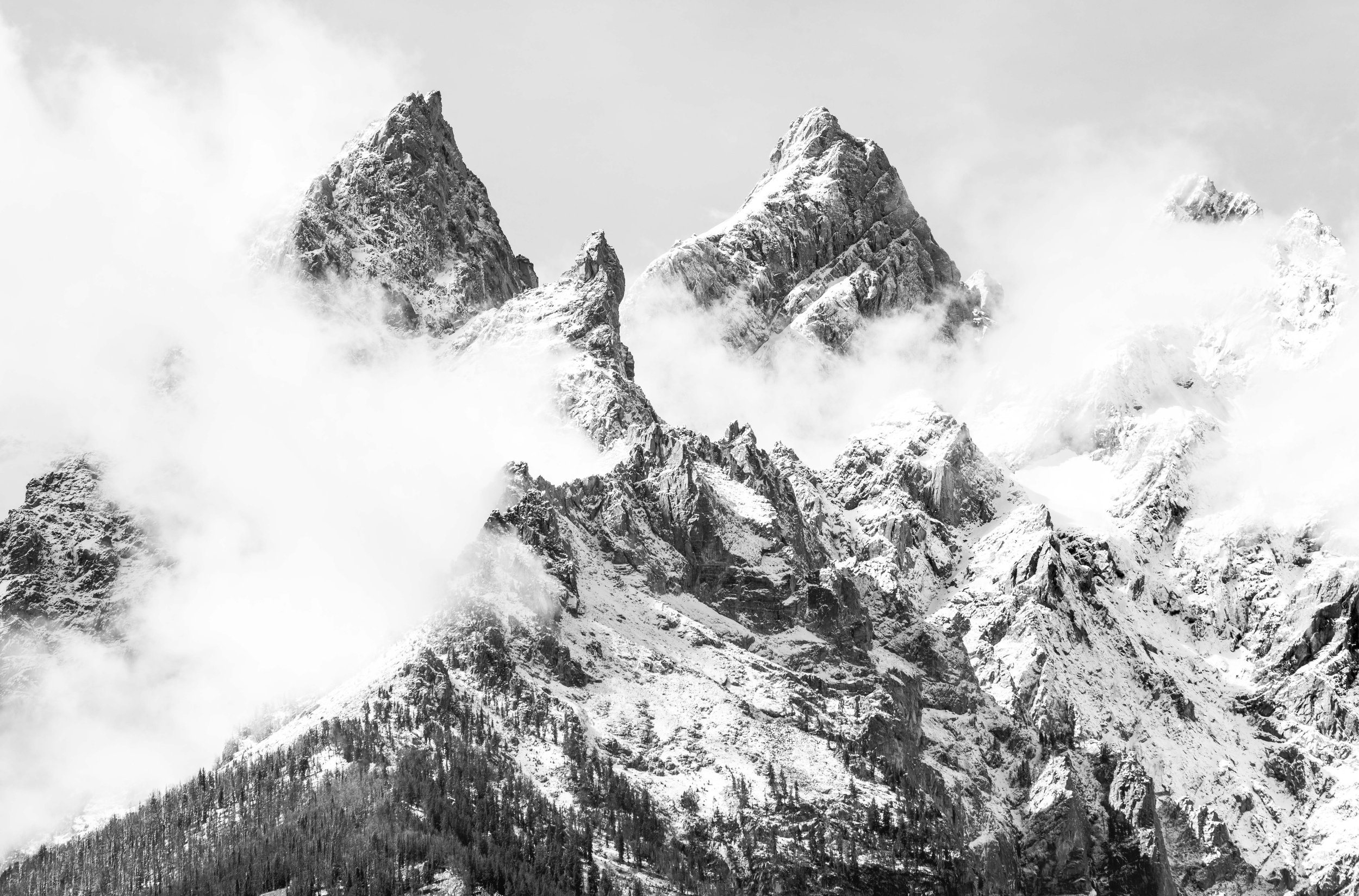 Black and white photo of a snowy mountain peak with cloud cover
