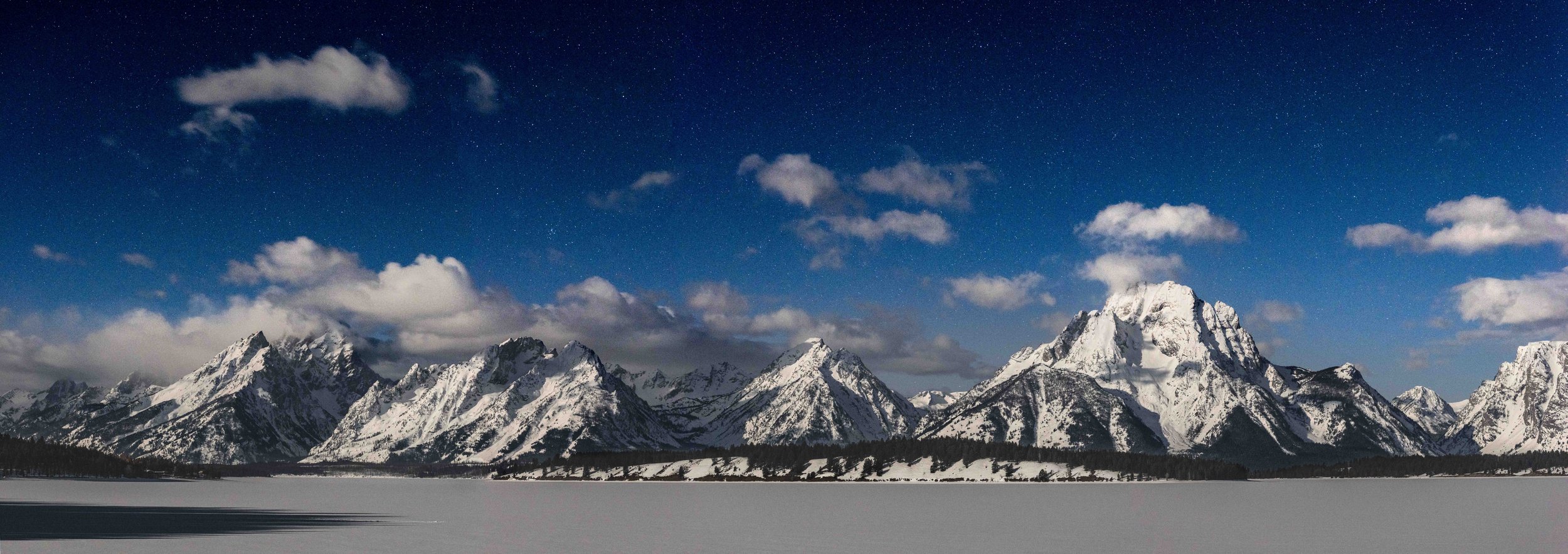 Snow-covered mountain range under a starry night sky.