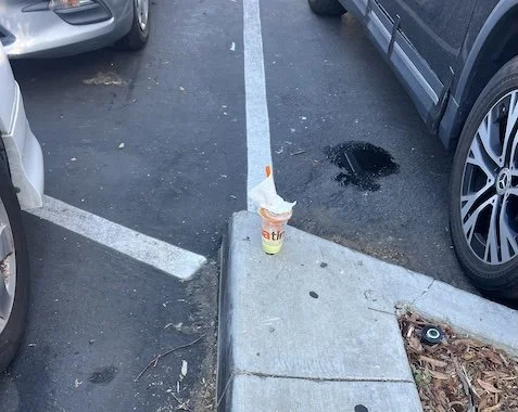 Discarded cup on a curb in a parking lot.