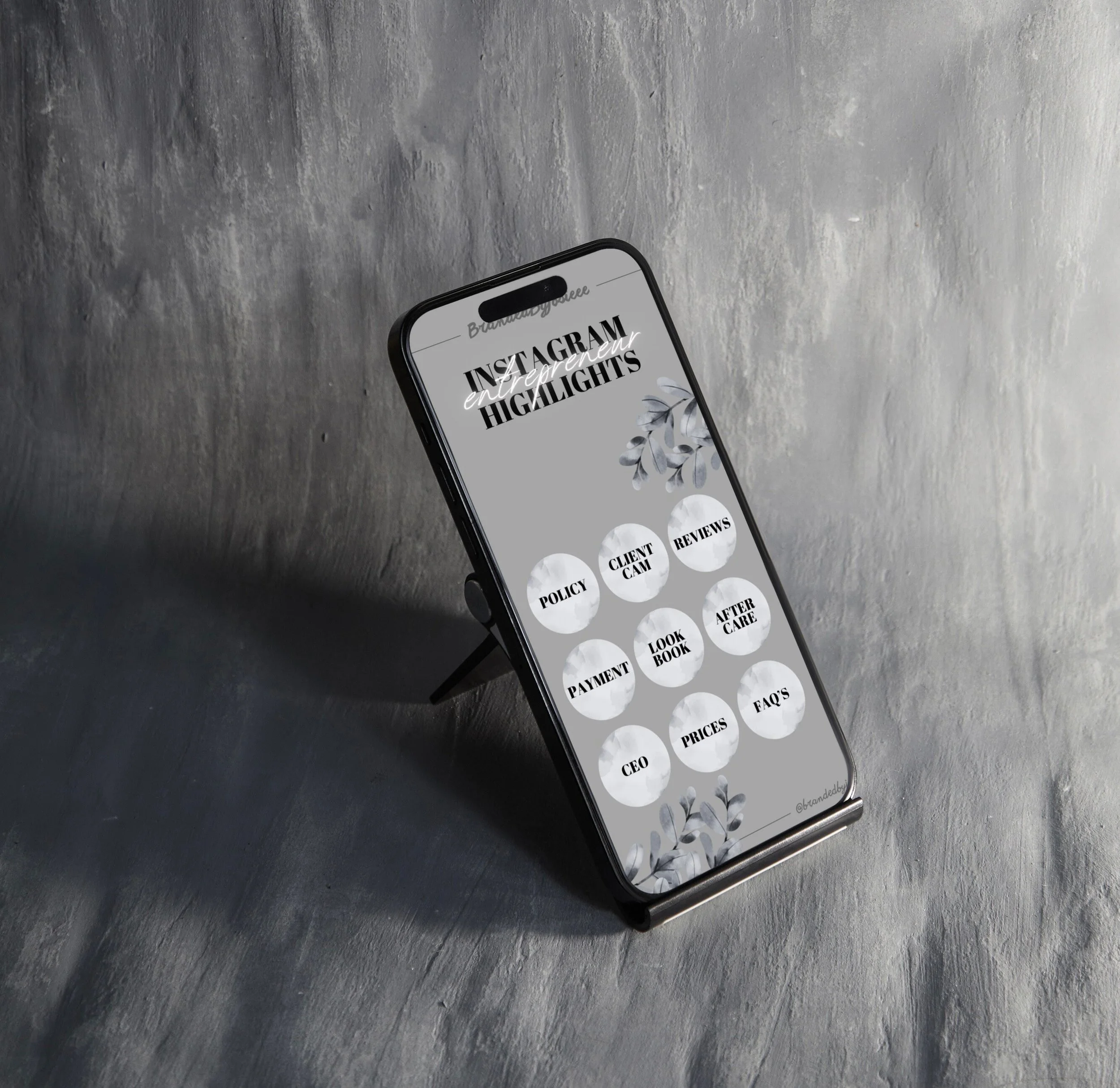 Smartphone on a stand displaying a menu for Instagram highlights with circular icons labeled Policy, Client Cam, Reviews, Payment, Look Book, After Care, CEO, Prices, FAQs, with decorative leaves in the background.