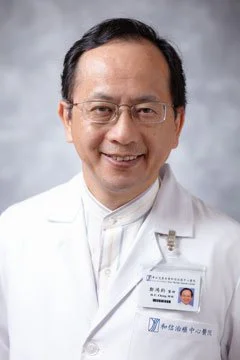 A male doctor wearing glasses and a white lab coat, smiling.