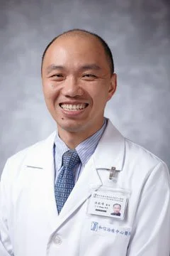 Portrait of a smiling male doctor in a white coat with a stethoscope. background is gray.