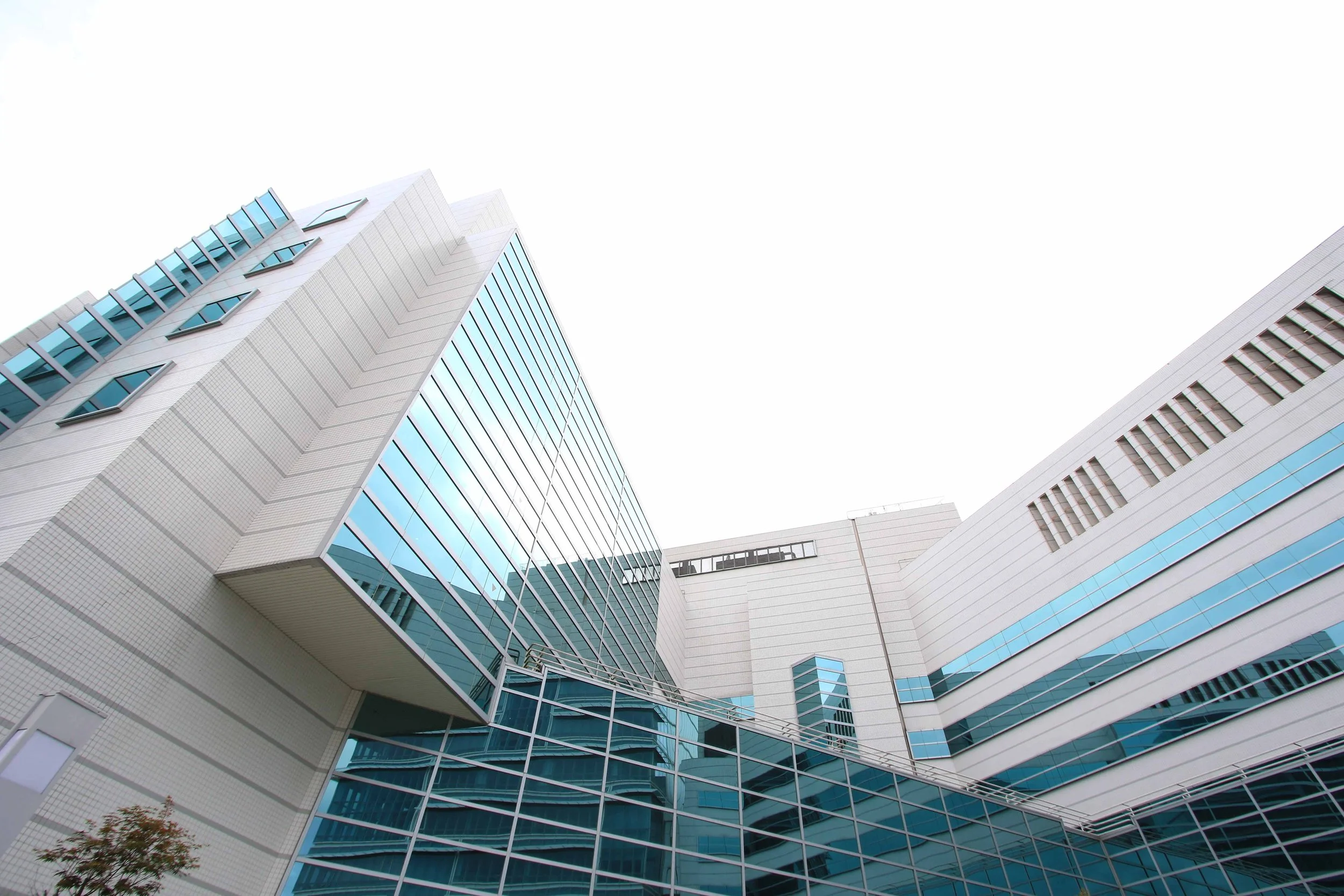 Modern multi-story building with glass windows and white exterior walls from a low-angle perspective.