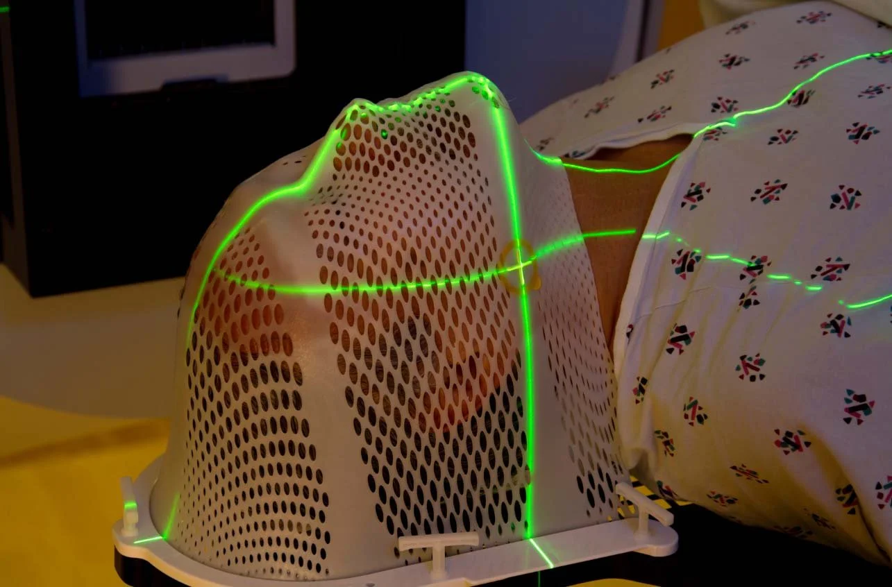 A medical device used for phototherapy or light therapy, with green laser lines projecting onto a patient in a hospital setting.