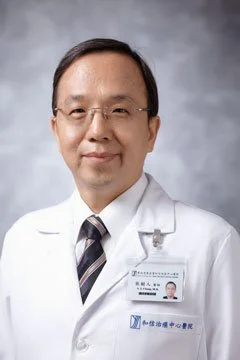 Professional portrait of an Asian male doctor wearing glasses, a white lab coat, and a name badge, against a gray background.