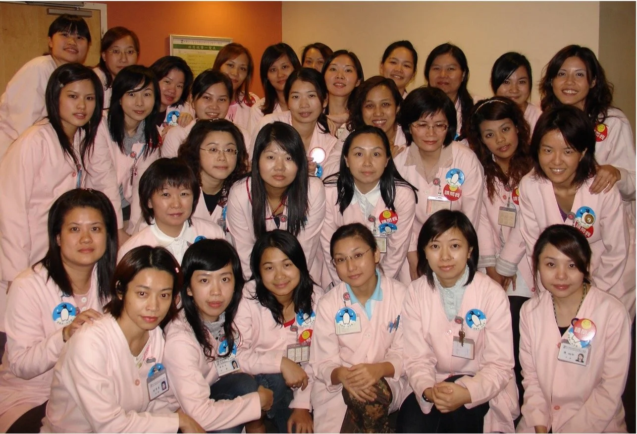 Group of women in pink uniforms posing for a photo indoors.