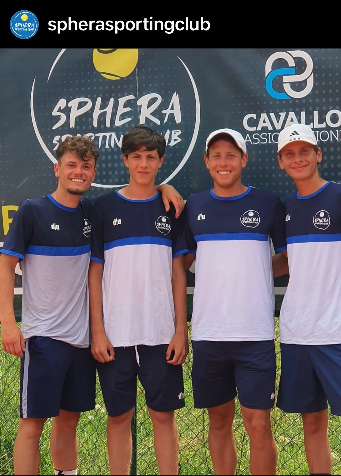 Quattro giovani uomini con abbigliamento sportivo, pose di squadra, in primo piano, sorridenti, con uno sfondo di sponsor e logo del club, sull'erba di un campo da tennis.