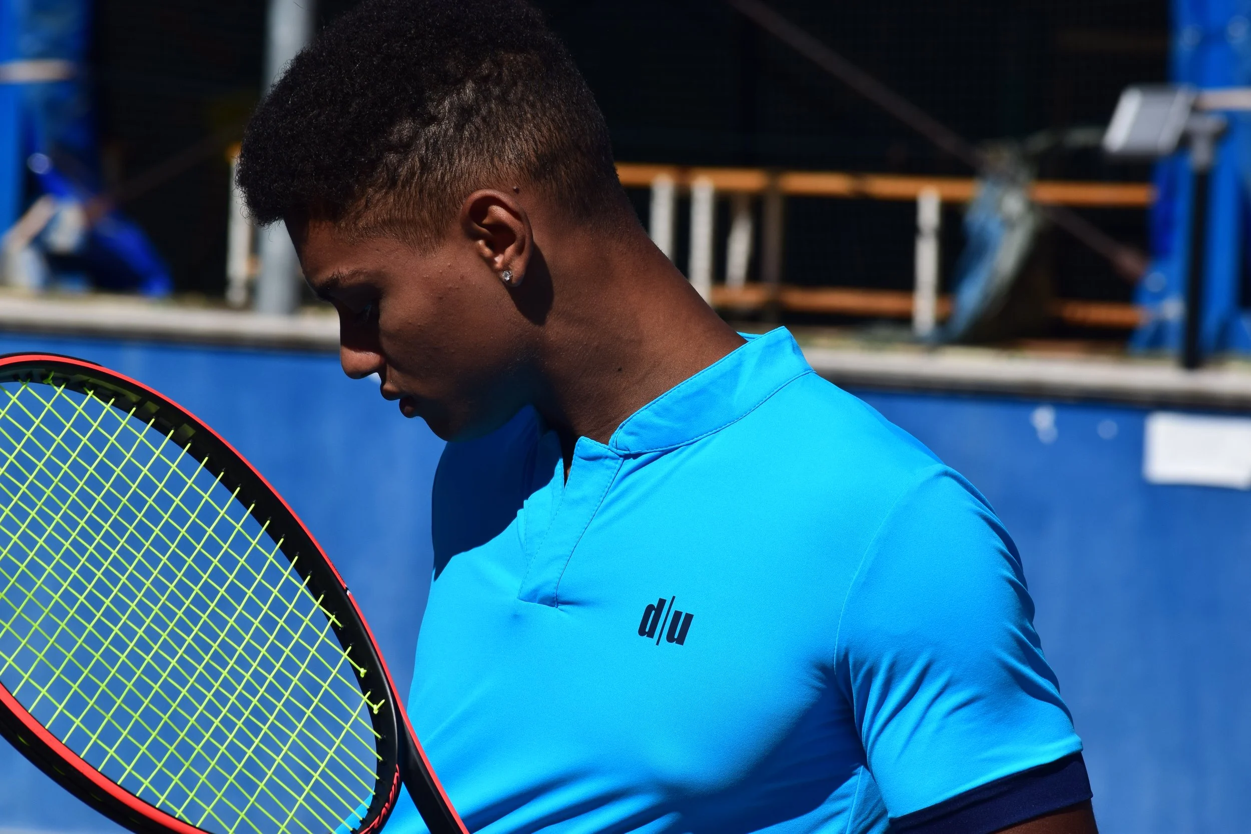 Giocatore di tennis indossa una maglietta azzurra e tiene una racchetta