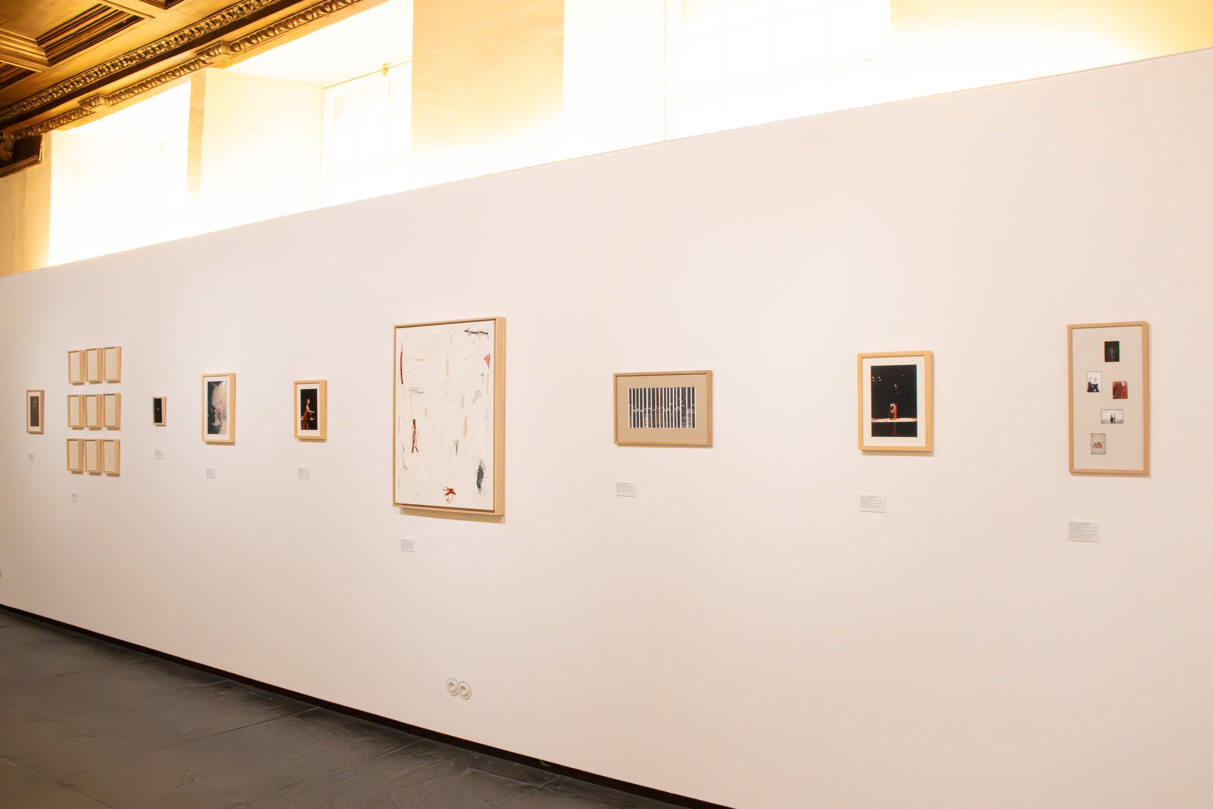 Gallery wall with various framed artworks in an art museum or gallery.