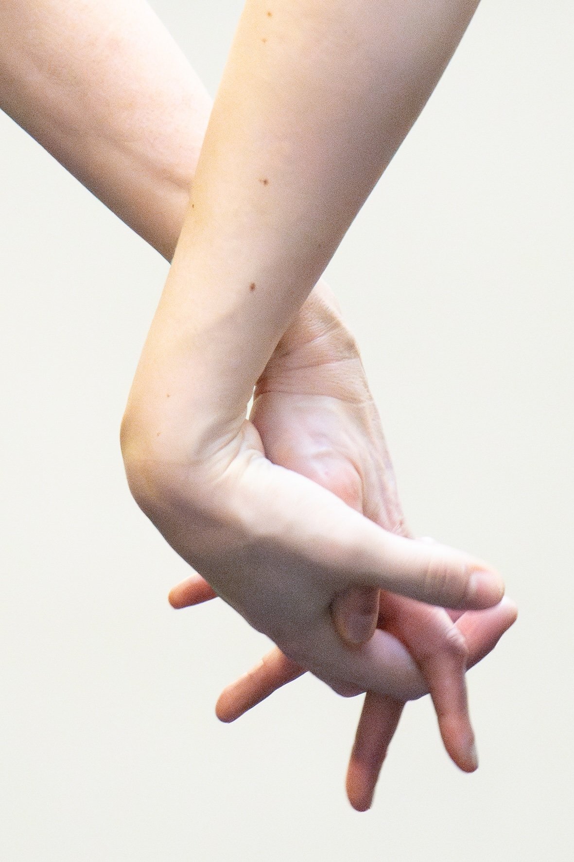 Close-up of a hand with long fingers, positioned against a plain background.
