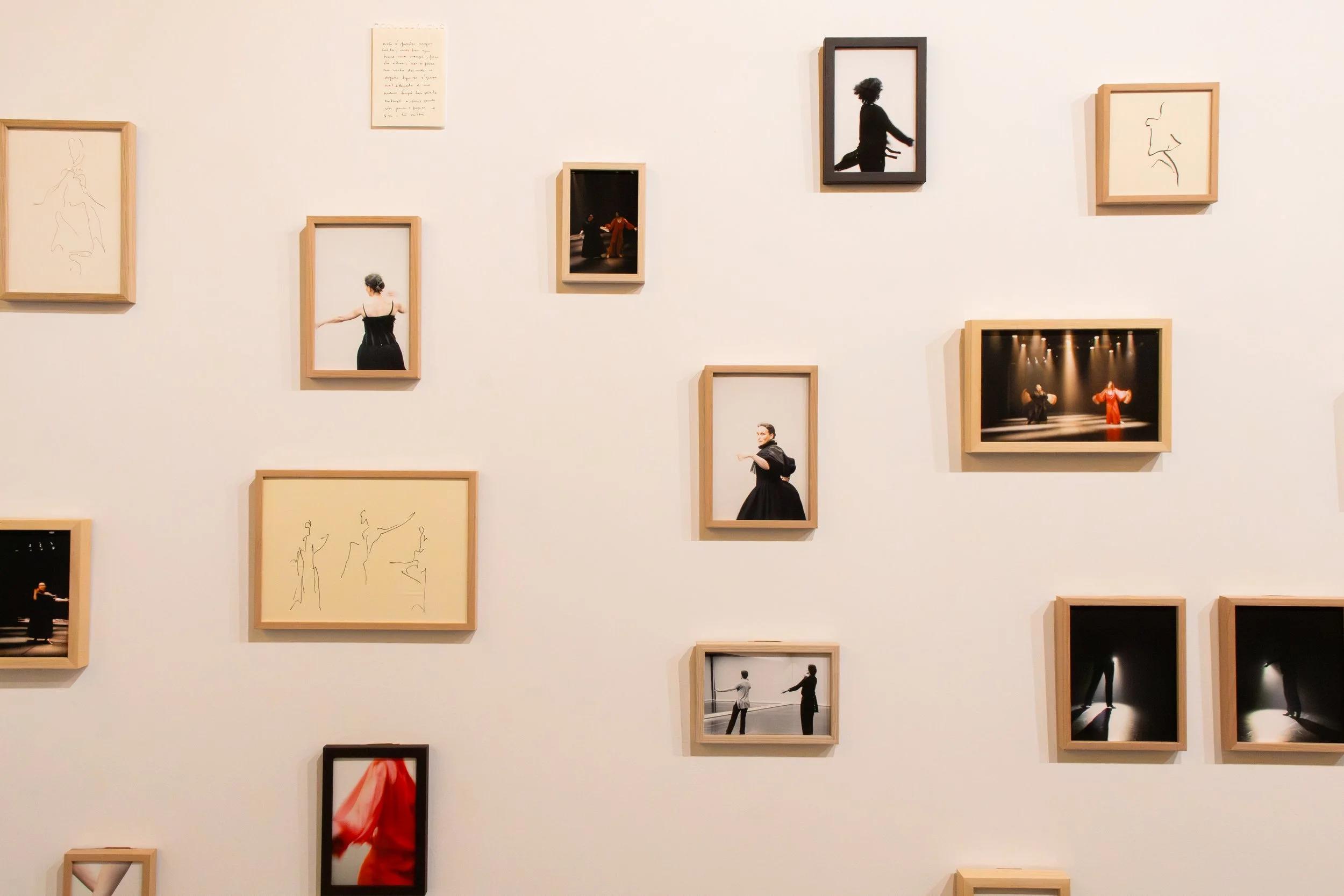 Gallery wall with framed photographs and sketches, showcasing dancers in various poses and stage performances.