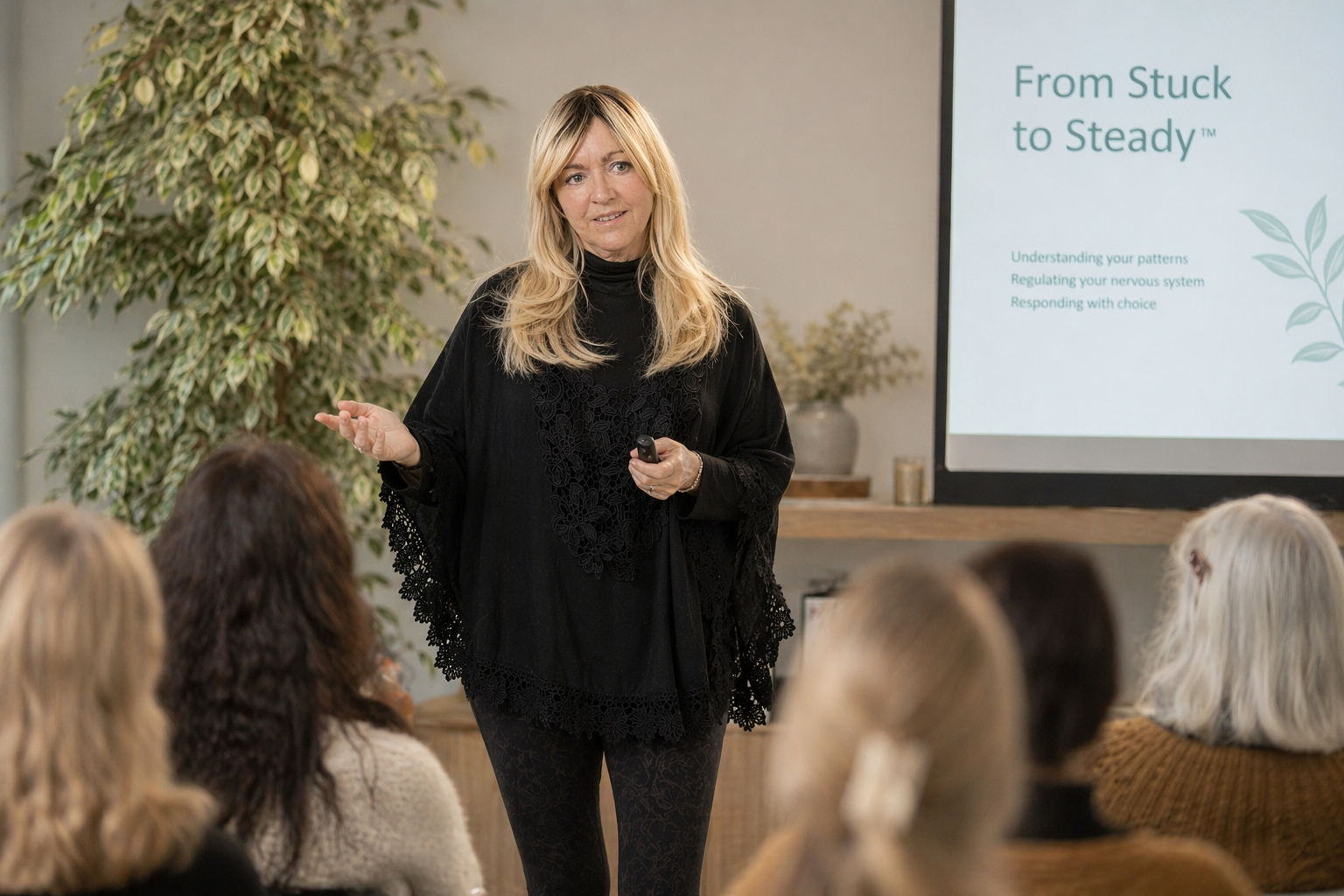 Trauma informed psychotherapy Northwest England, anxiety and stress support provided in a presentation to a group of people, at a workshop with a slide titled 'From Stuck to Steady visible on a screen behind Michelle Courtney.