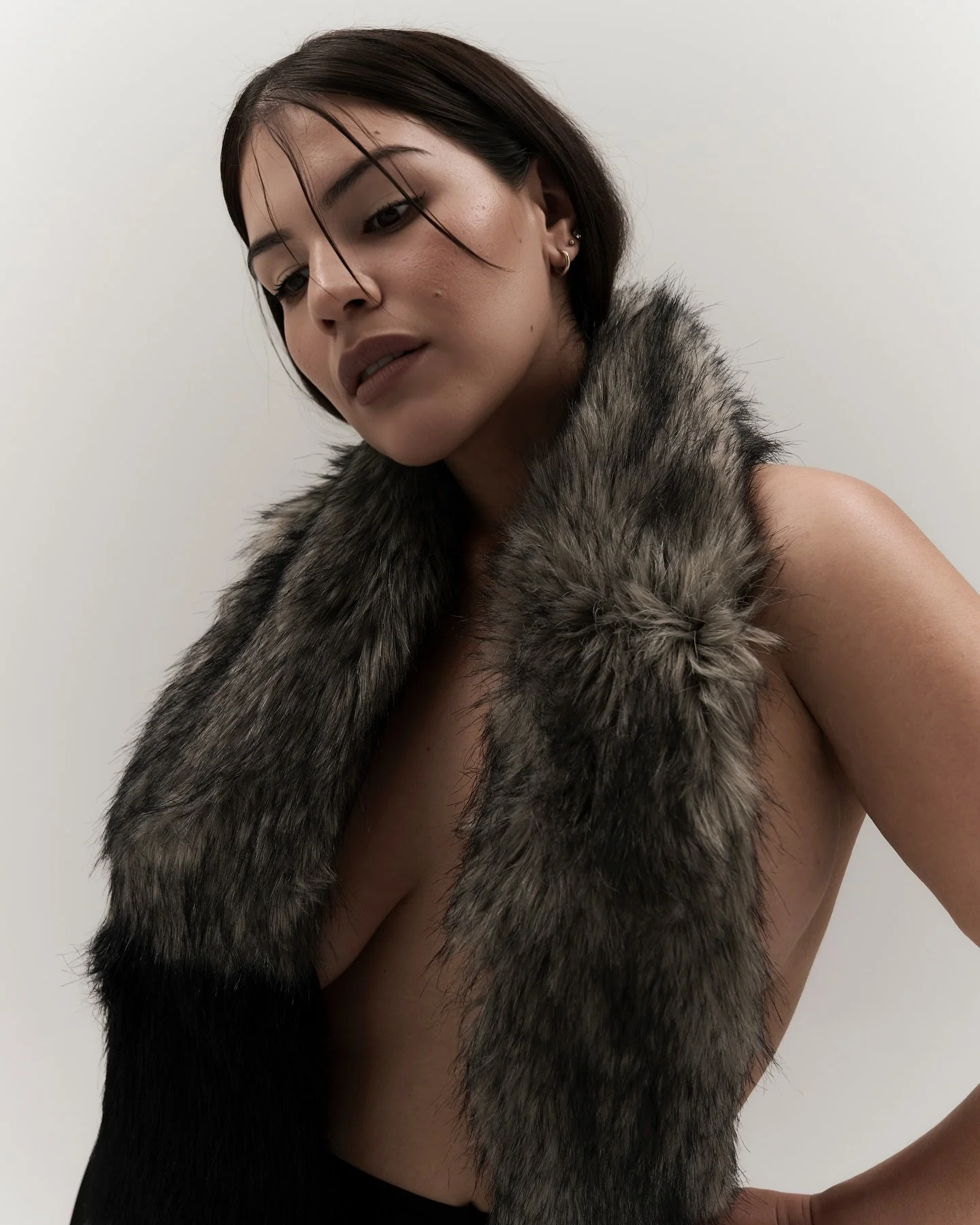 Fashion editorial portrait of Vannia in a fur-textured garment against a pale studio background.