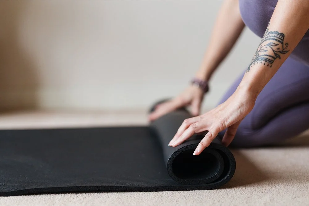 A close up of Nikkis hands rolling out her yoga mat