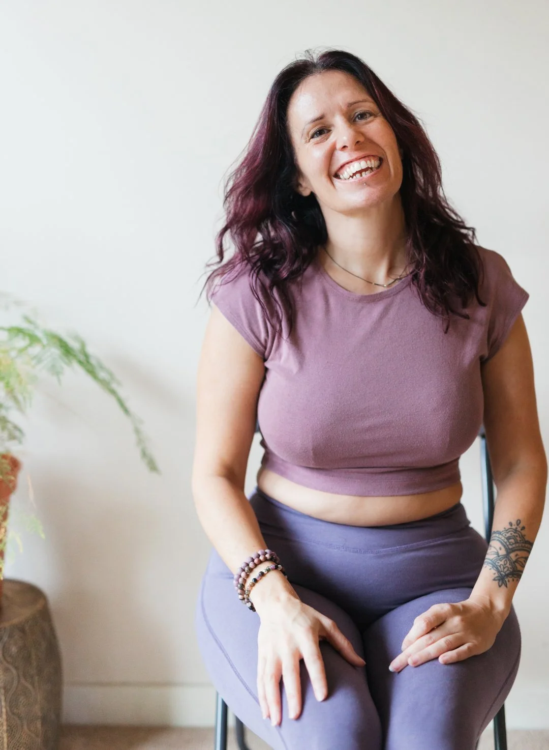 Nikki on a chair that she uses for chair yoga. She has a big smile like she is laughing.