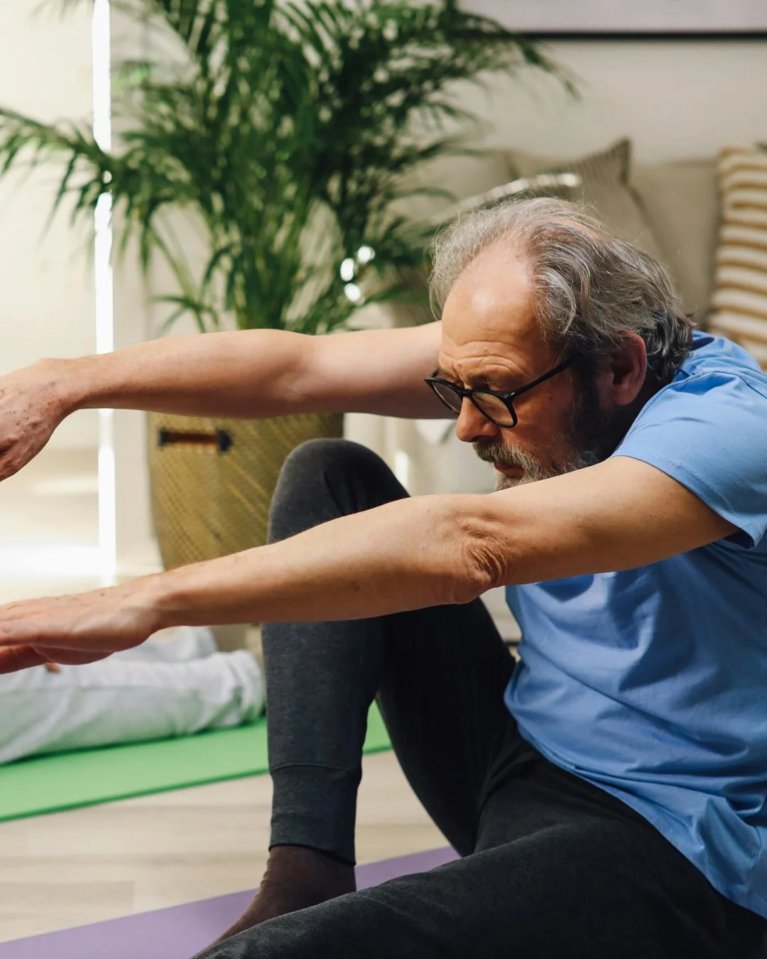 Someone doing yoga at home. They are in a seated position with their arms outstretched