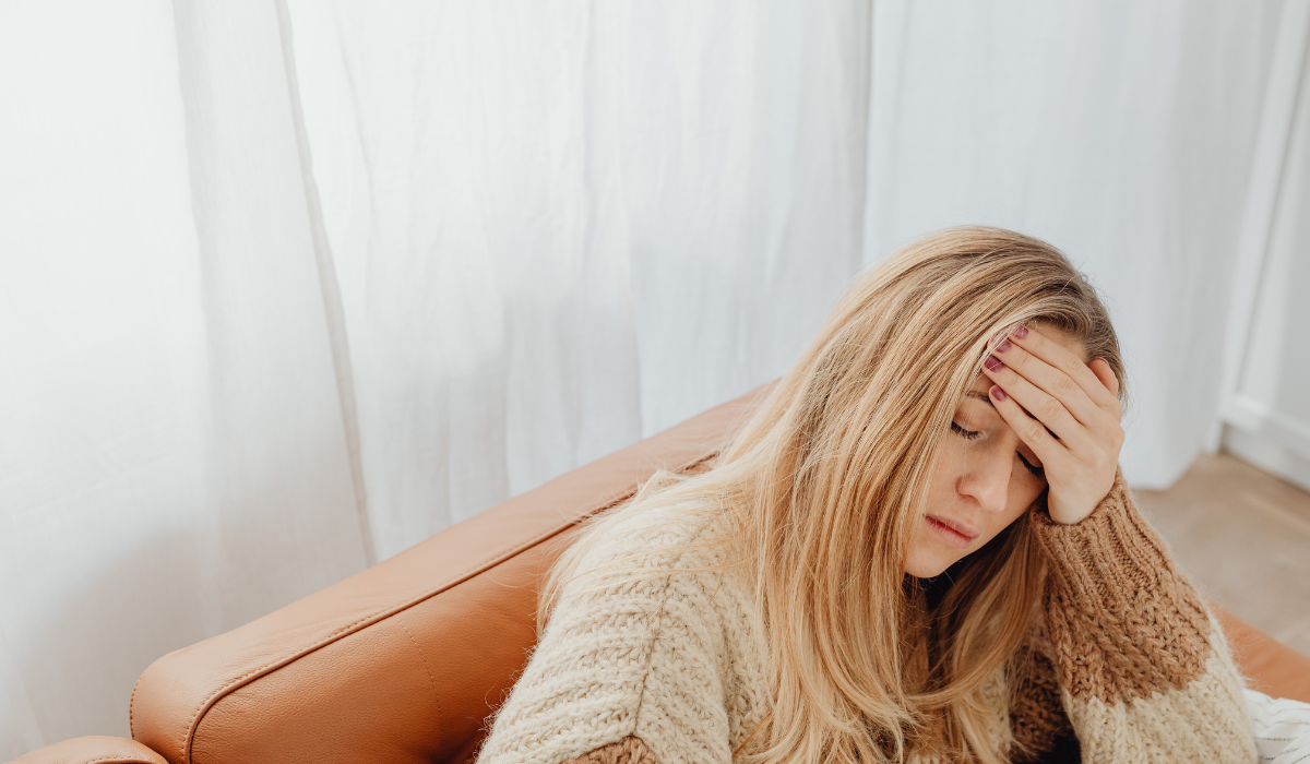 A woman holding her head looking tired and overwhelmed, reflecting on coping mechanisms and when to seek addiction therapy in Calgary
