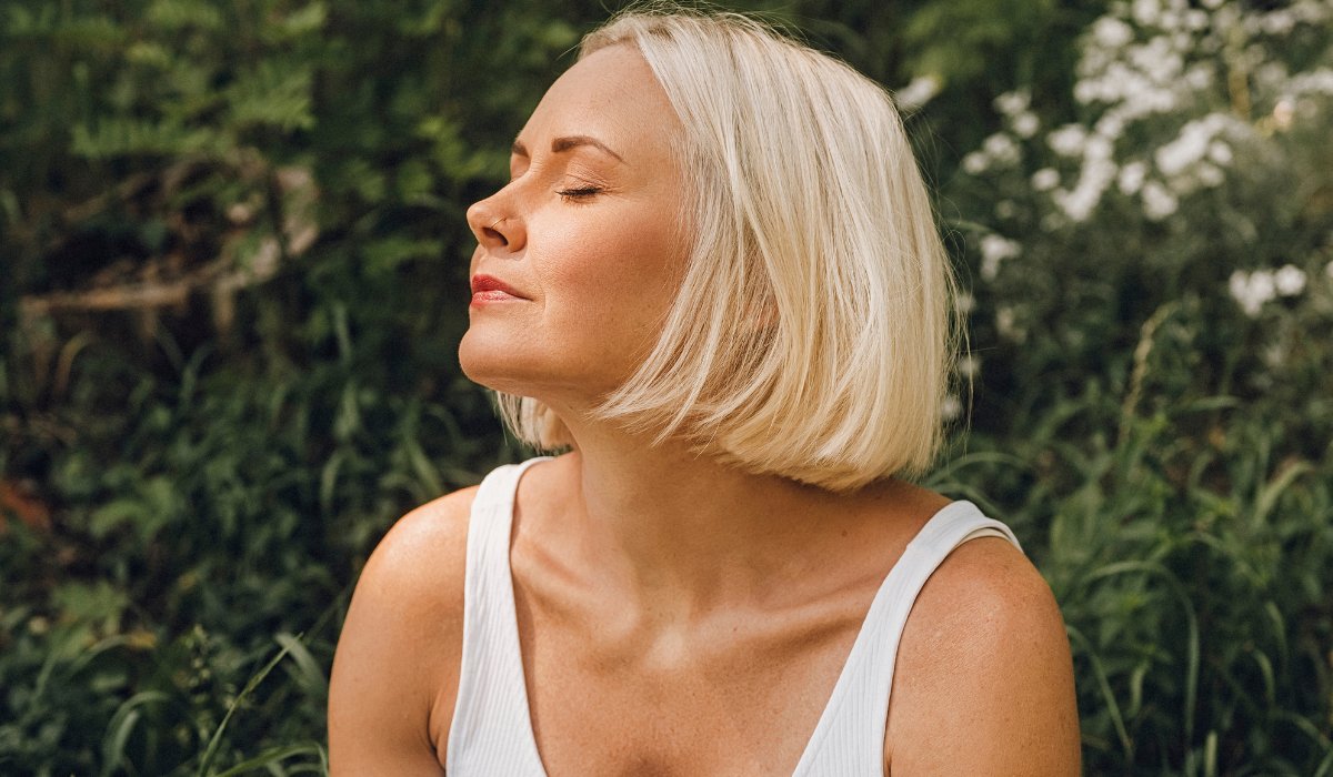 A woman taking a deep relaxing breath, reflecting on perimenopause and mental health support in Calgary