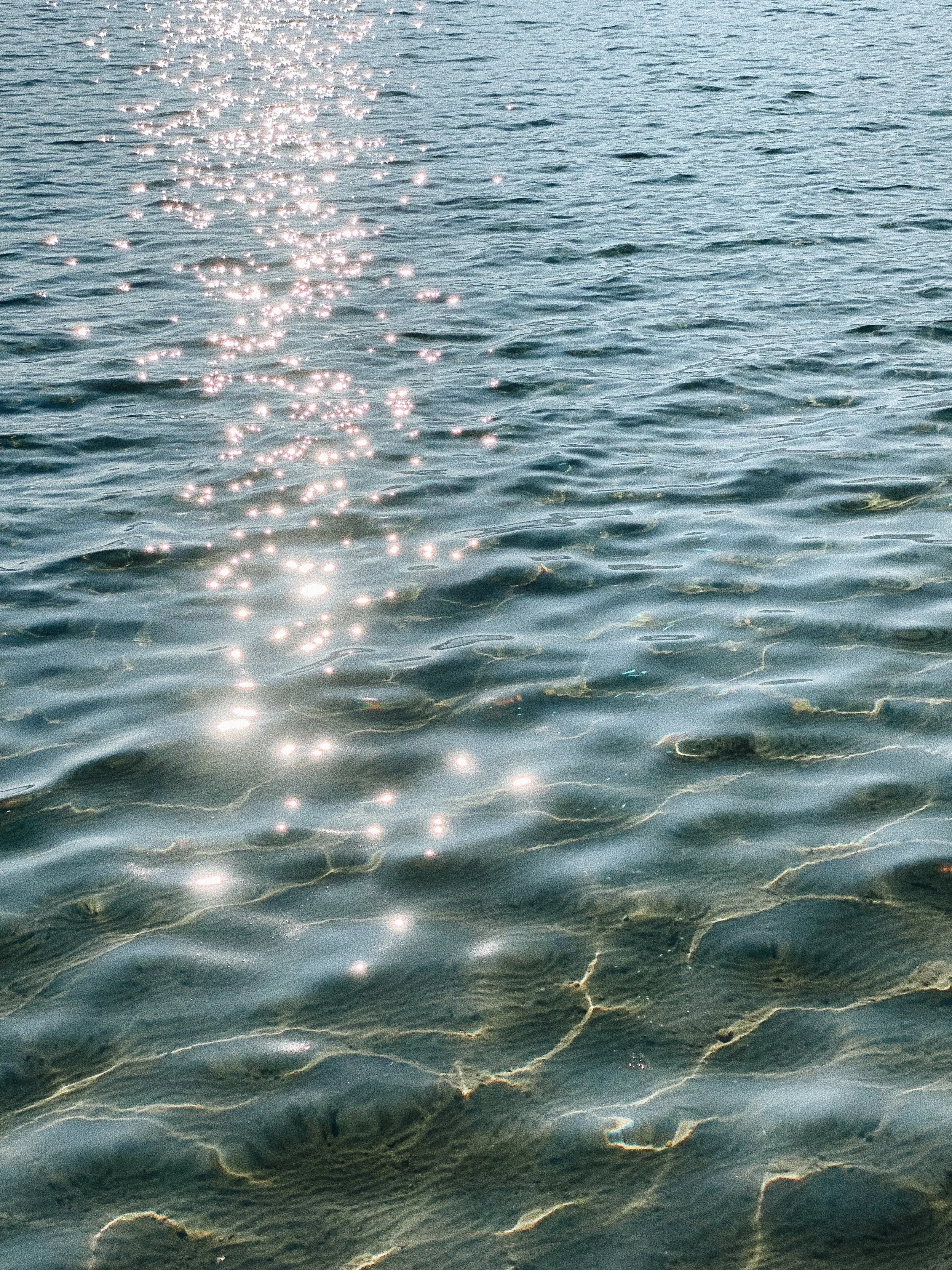 Une vue d'une étendue d'eau calme avec des reflets de lumière du soleil à la surface.