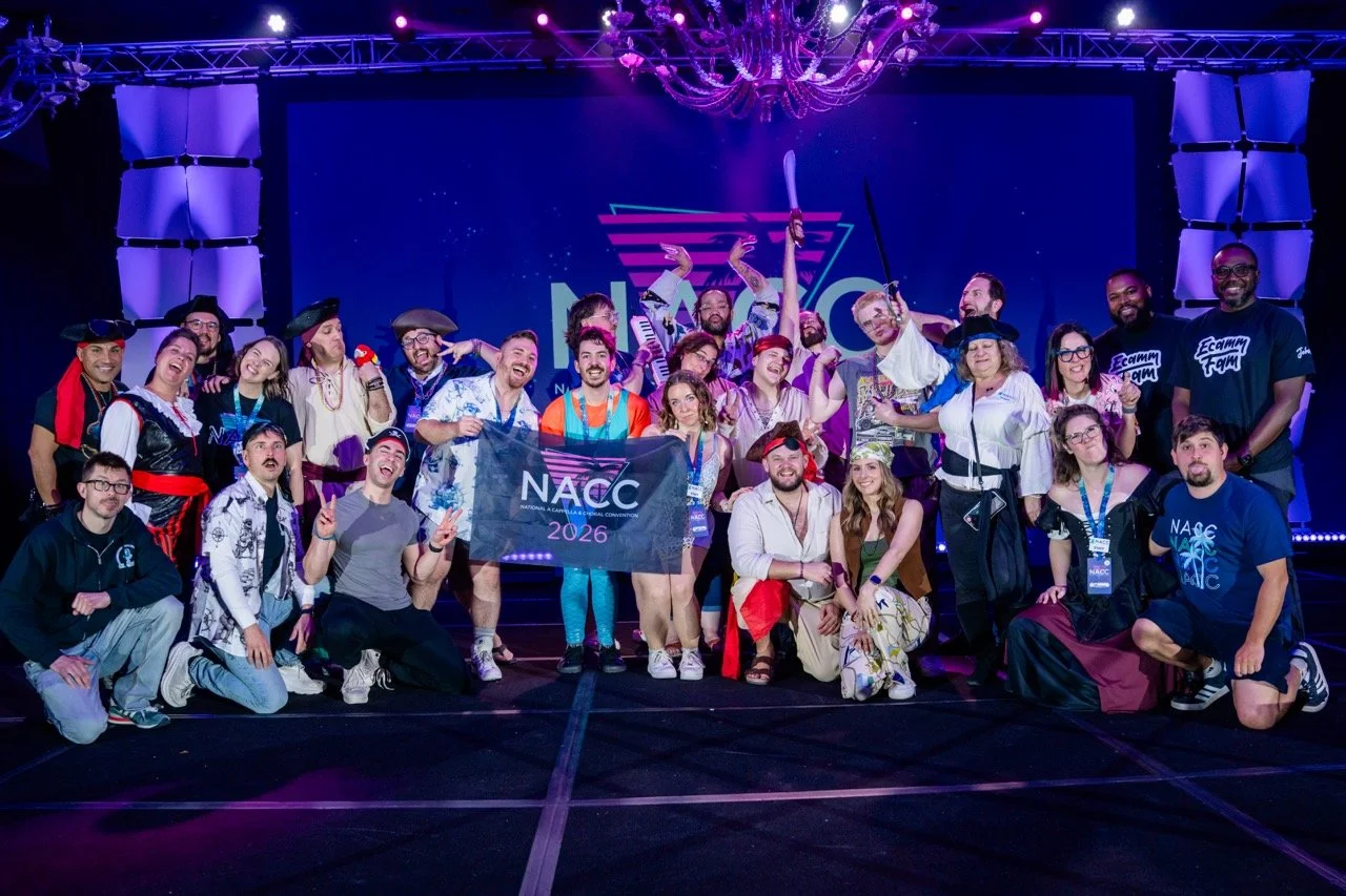 Group of people dressed in pirate costumes and casual attire, celebrating on stage at the 2026 NACC conference, with a large screen and purple lighting in the background.