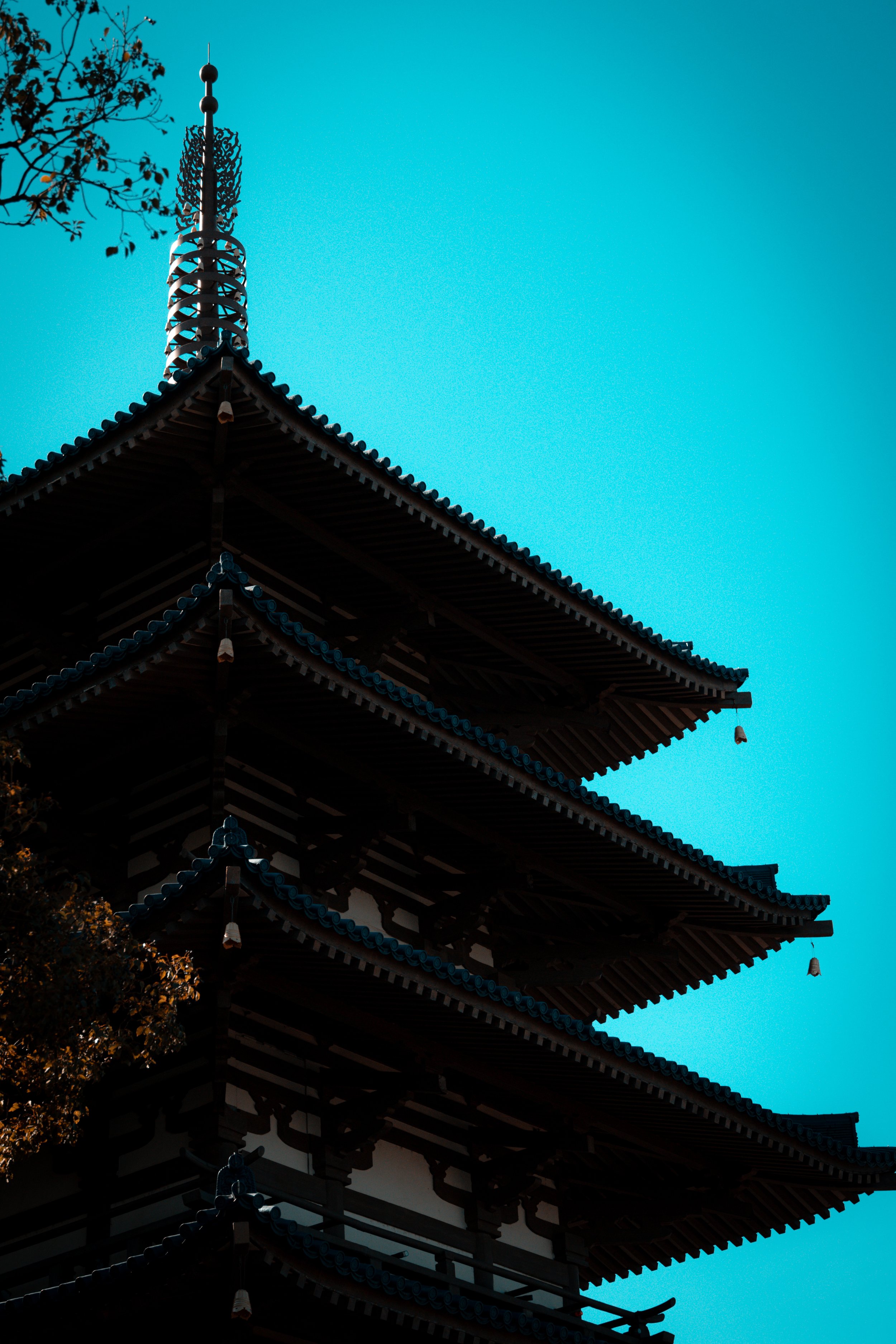 Silhouette of a traditional Japanese pagoda with multiple tiers and ornate roof details against a clear blue sky.
