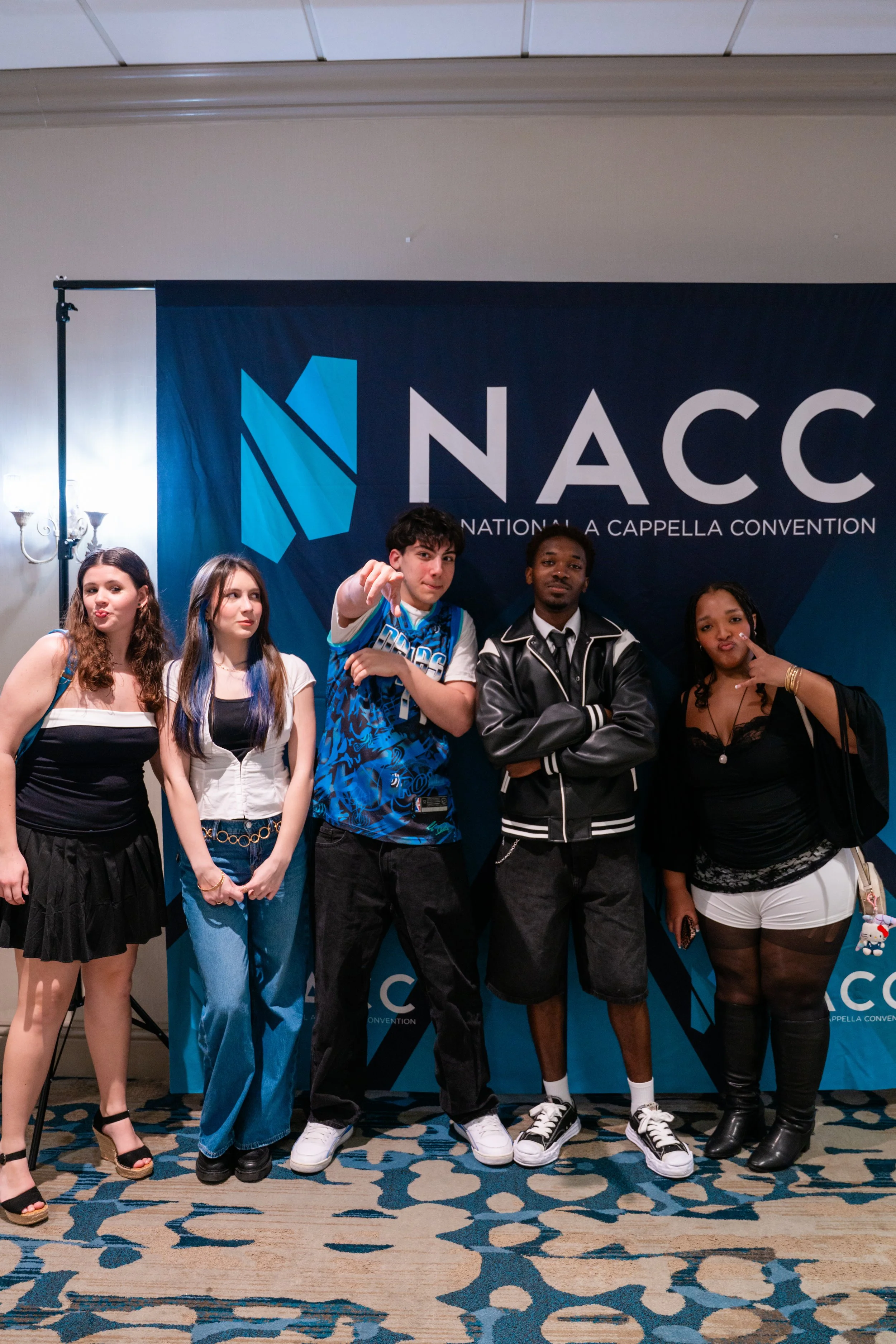 Group of five diverse young people posing in front of a NACCI banner at a convention.