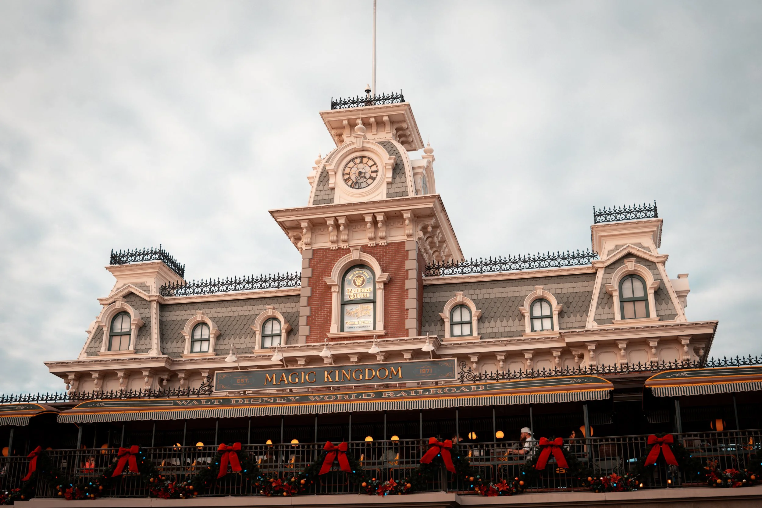 The historic Magic Kingdom train station at Walt Disney World decorated with Christmas garlands and red bows.
