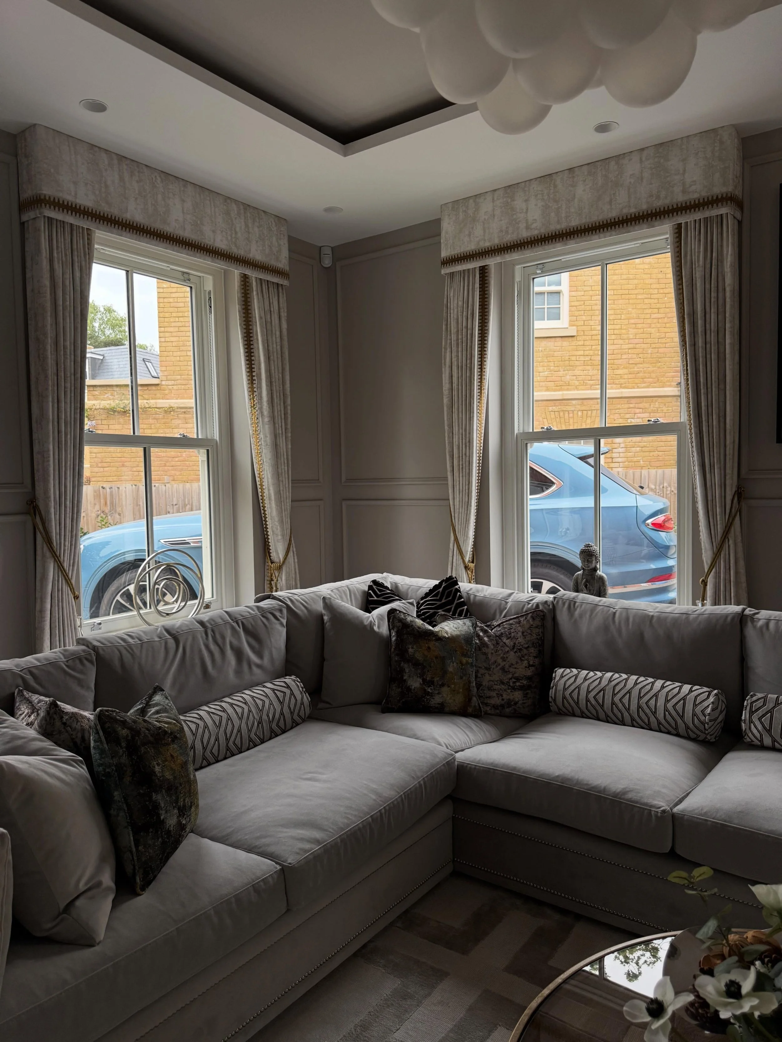 A sophisticated living room design featuring curtains with tailored pelmets, beautifully crafted in @prestigioustextiles Ceasar Coin fabric and finished with elegant @jimthompson.fabrics Opus gold tape trimming.
Complemented by coordinating handmade 