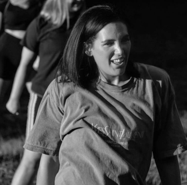 A woman in a grey t-shirt smiling warmly.