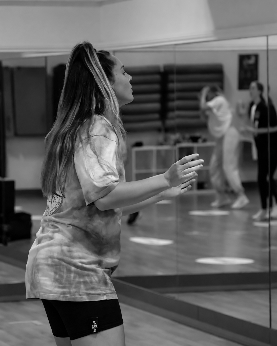 A woman in a tie dye shirt smiling for a picture, radiating a vibrant and carefree aura.