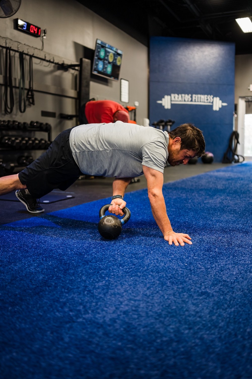  A man performing a push-up on a blue mat with kettlebell