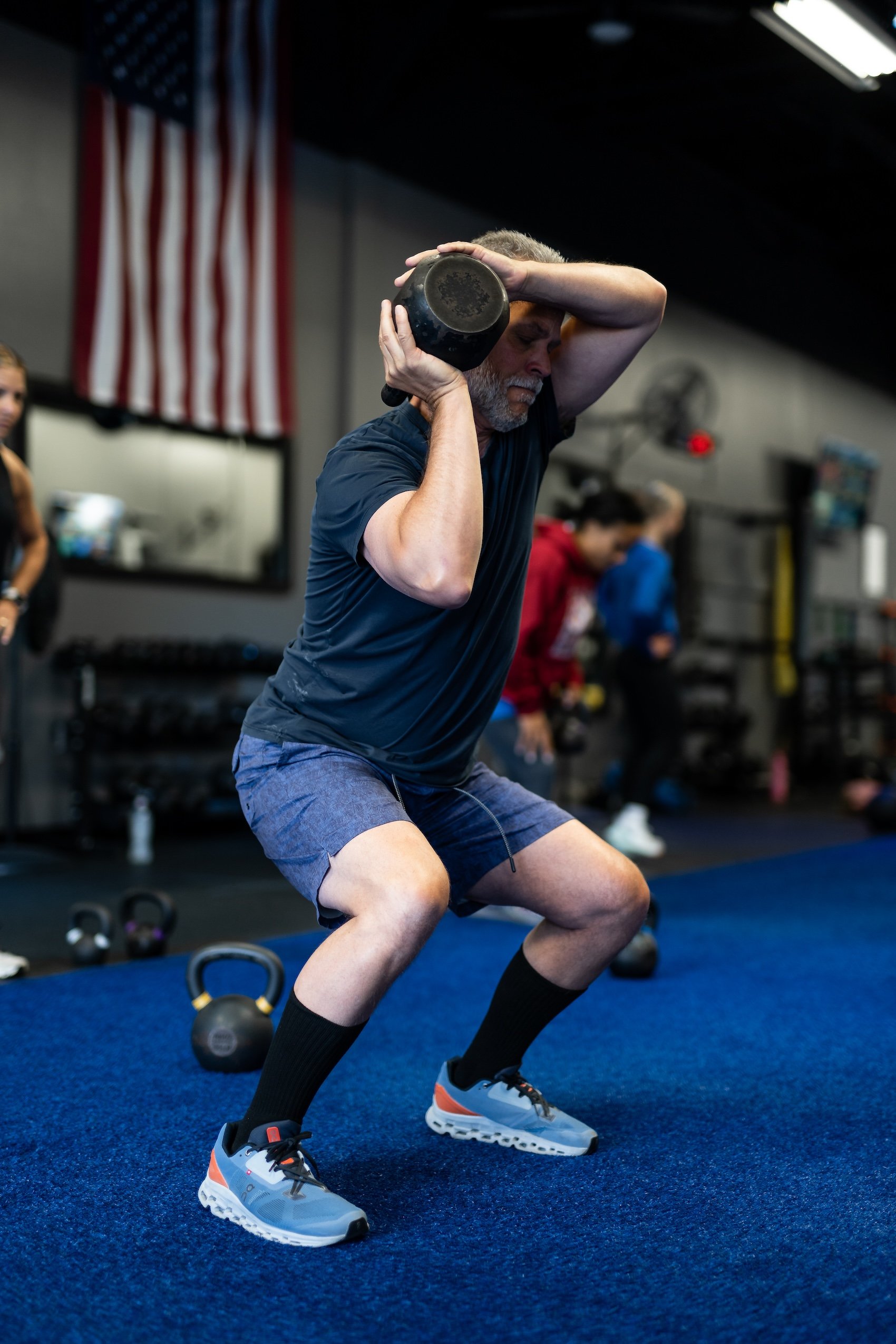 A man doing a squat with a kettlebell in a gym, working on his strength and fitness.